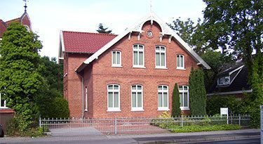 Ein großes Backsteinhaus mit rotem Dach und weißen Verzierungen