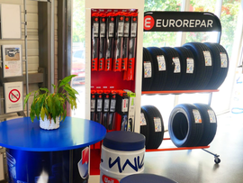 Présentoir de magasin de pièces automobiles avec pneus, porte-outils rouge et table bleue avec plantes
