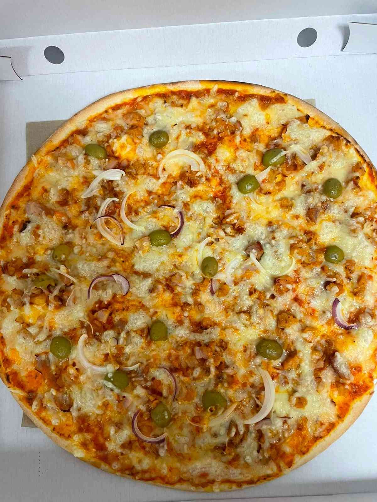 Pizza de queso y verduras en la tapa de una caja blanca