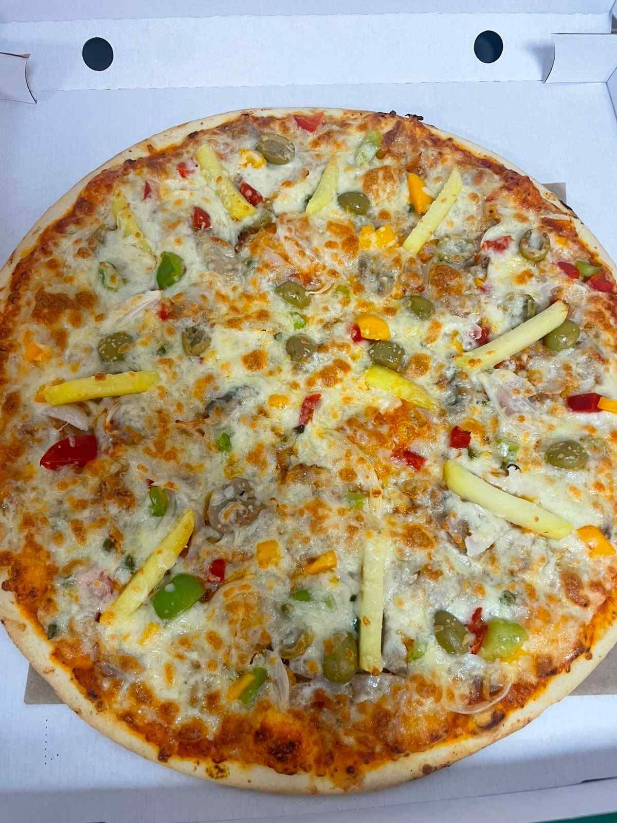 Pizza de queso con ingredientes rojos y amarillos en una caja blanca abierta.