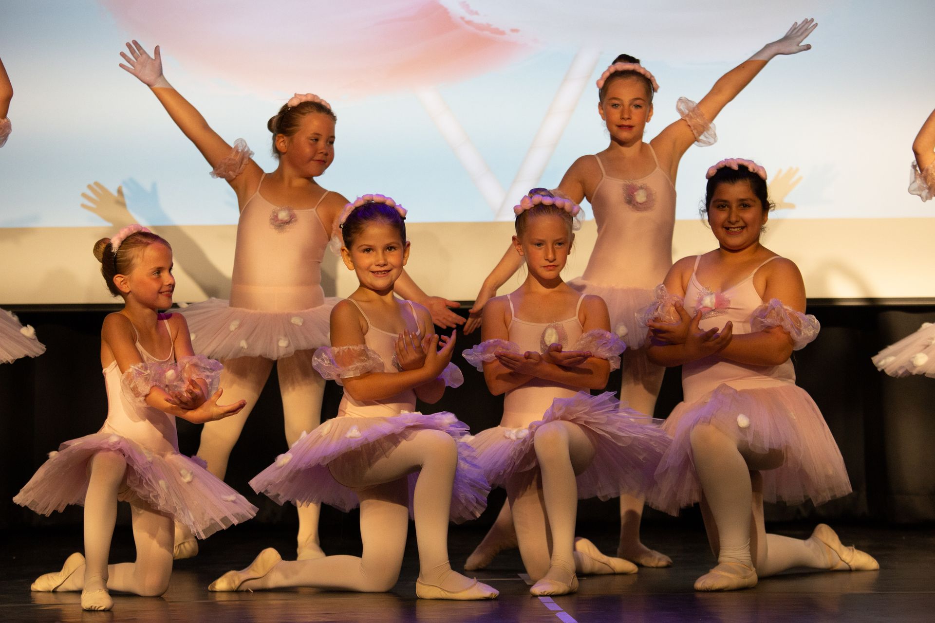 Kinder in weißen Ballettkostümen sitzen auf der Bühne