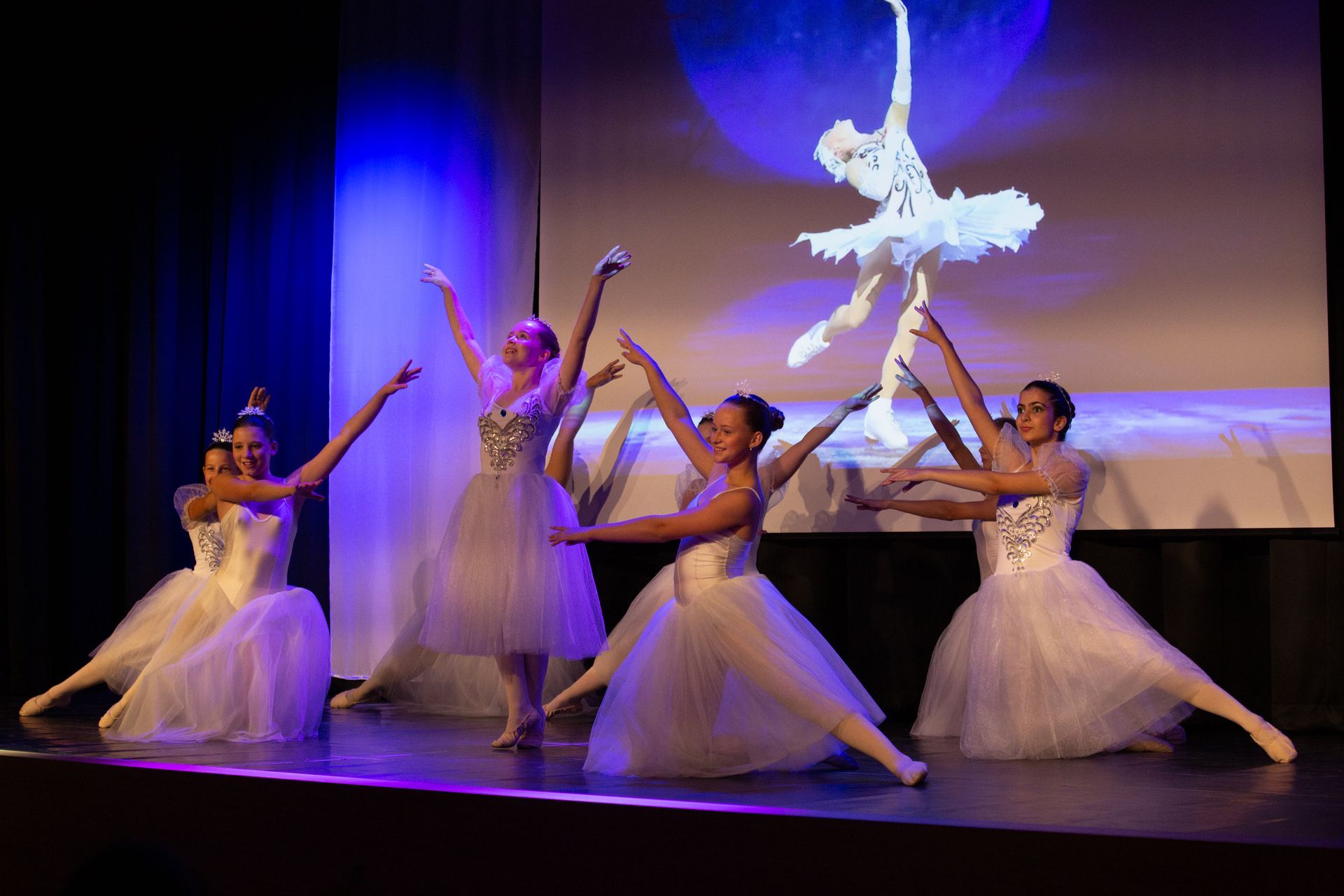 Tänzerinnen in weißen Ballett-Kleidern tanzen unter blauem Licht
