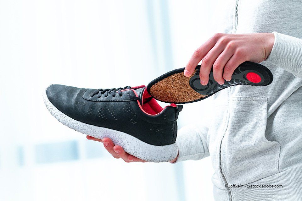 Person hält Schuh und Einlage ins Bild