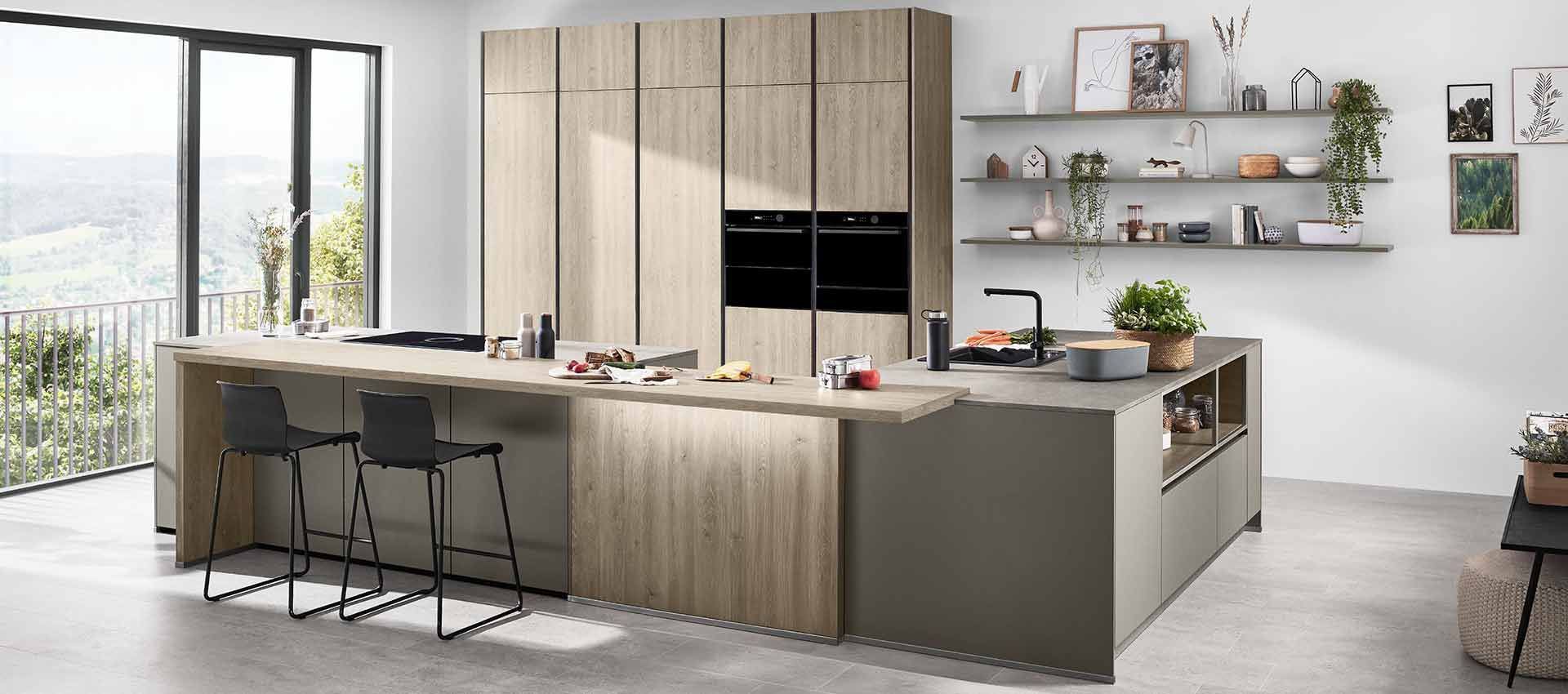 Moderne Küche mit hellen Holzschränken, großer Kochinsel, Barhockern und offenen Regalen an einem hellen Fenster