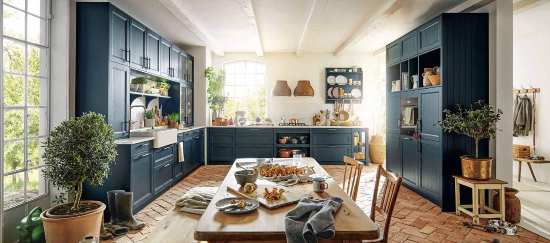 Helle, moderne Küche mit marineblauen Schränken, langer Kochinsel und Sonnenlicht, das durch große Fenster strömt.