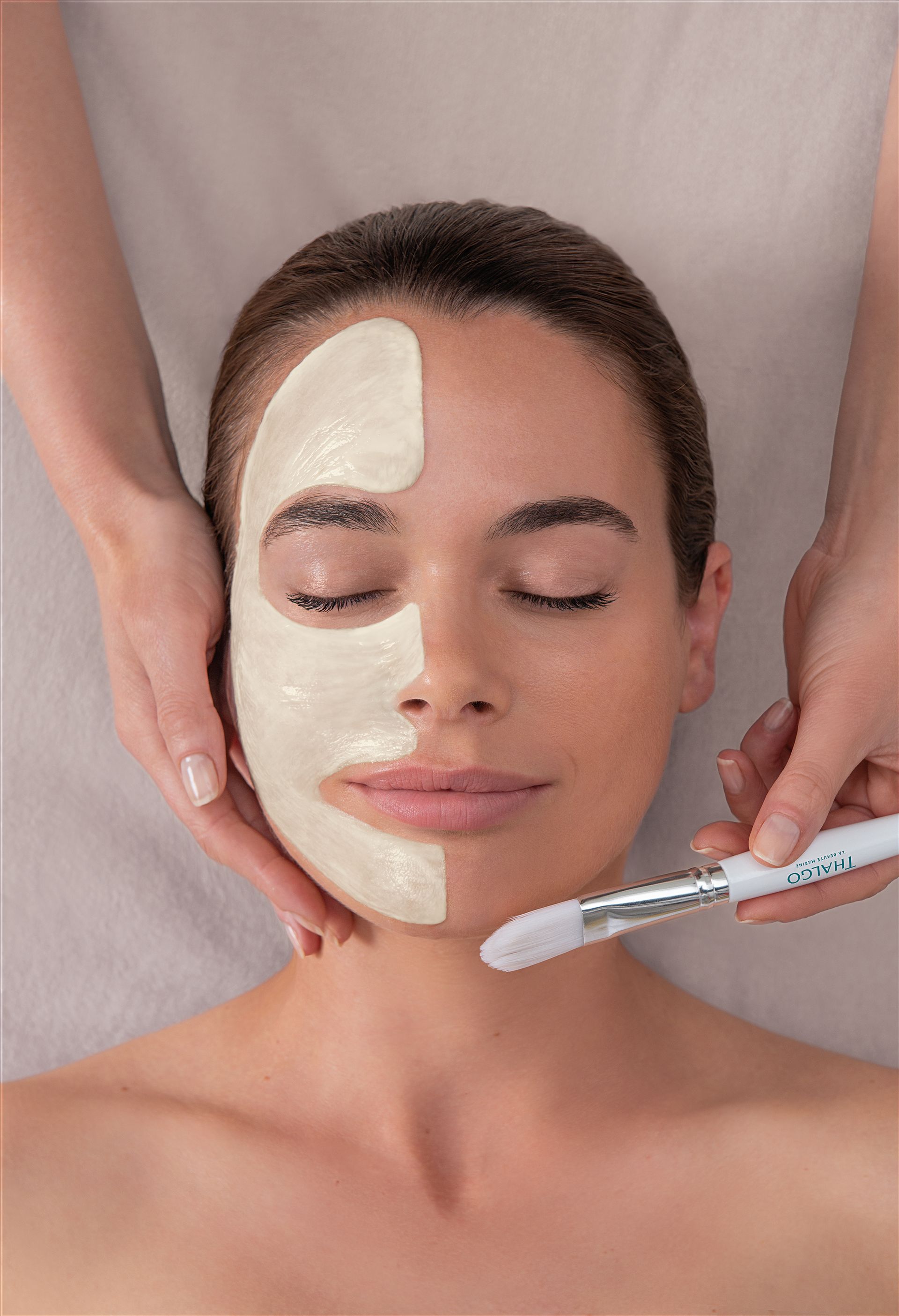 Soin du visage en spa, avec une crème appliquée et une brosse qui lisse le produit sur le visage d’une femme