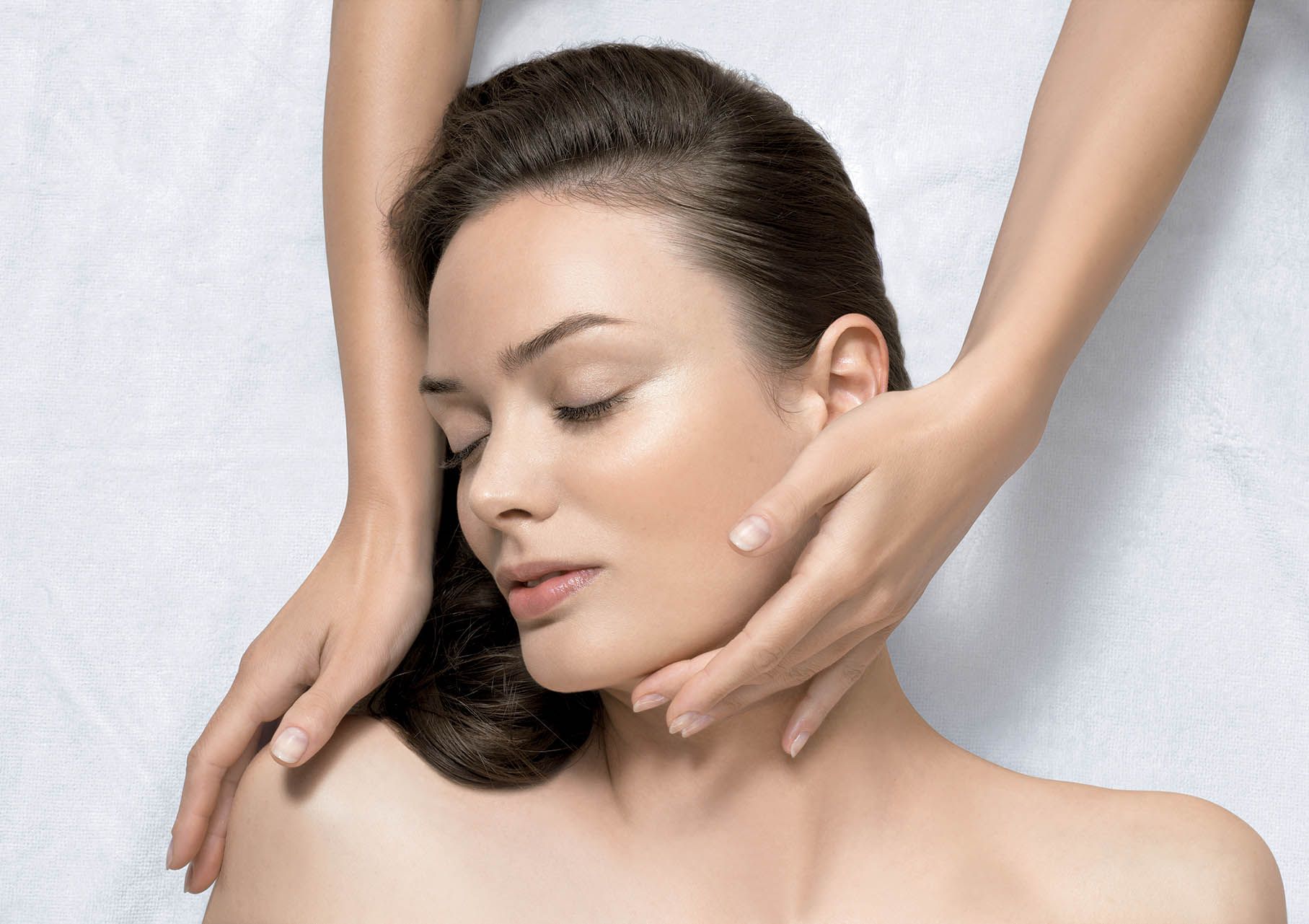Femme recevant un massage relaxant du cou et des épaules sur une table de spa blanche