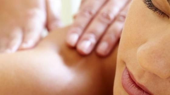 Gros plan d’une personne recevant un massage des épaules, les mains appuyant sur la peau