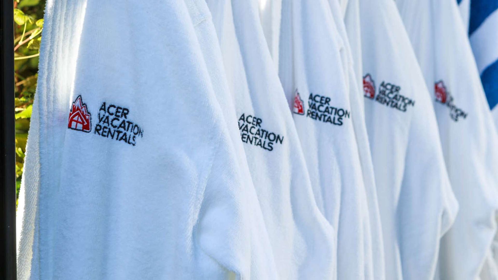 White shirts with embroidered “Acer” and “Rivendell” logos hanging in a row