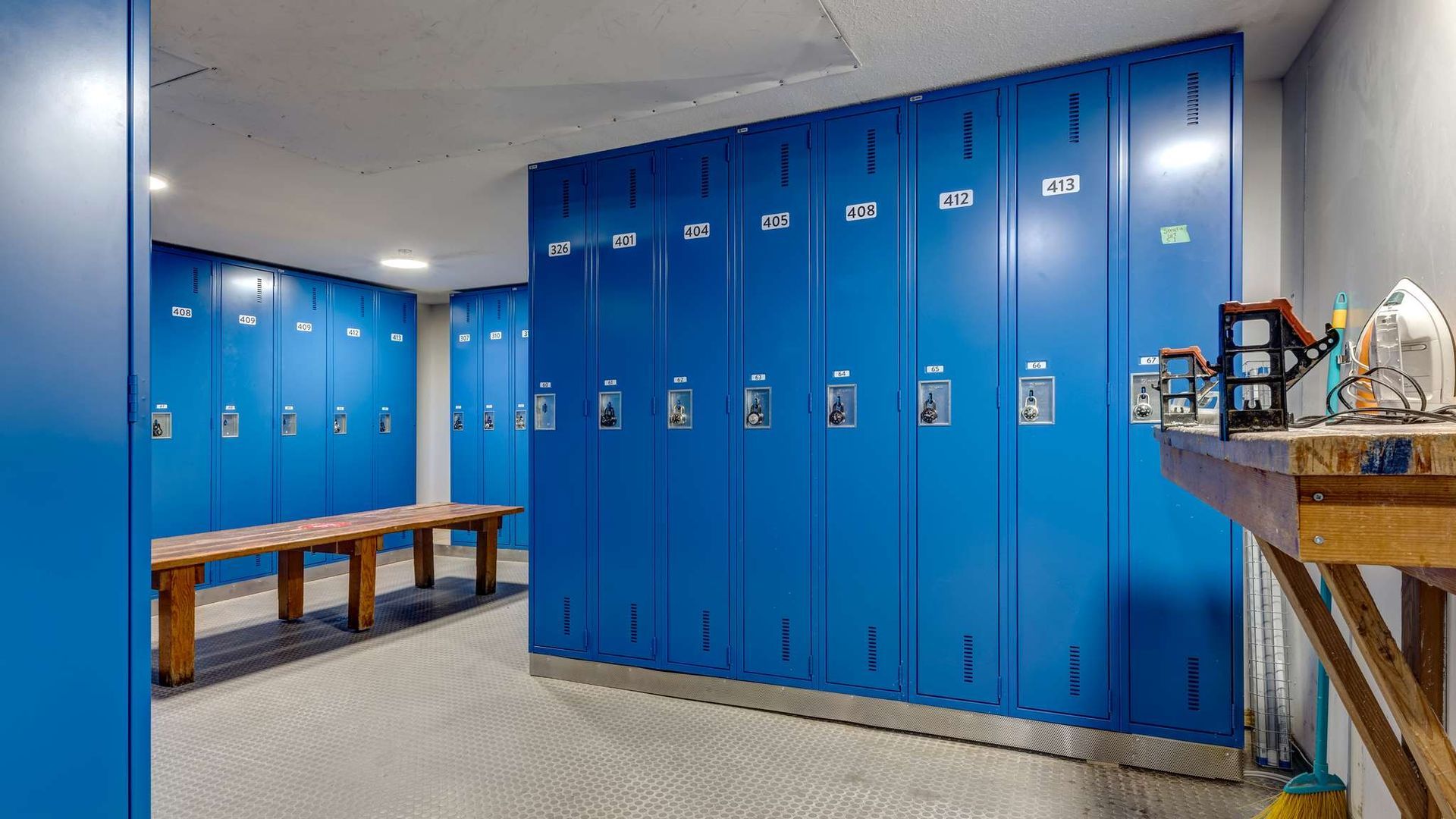 Blue locker room with benches, gray carpet, and shelves along the right wall.