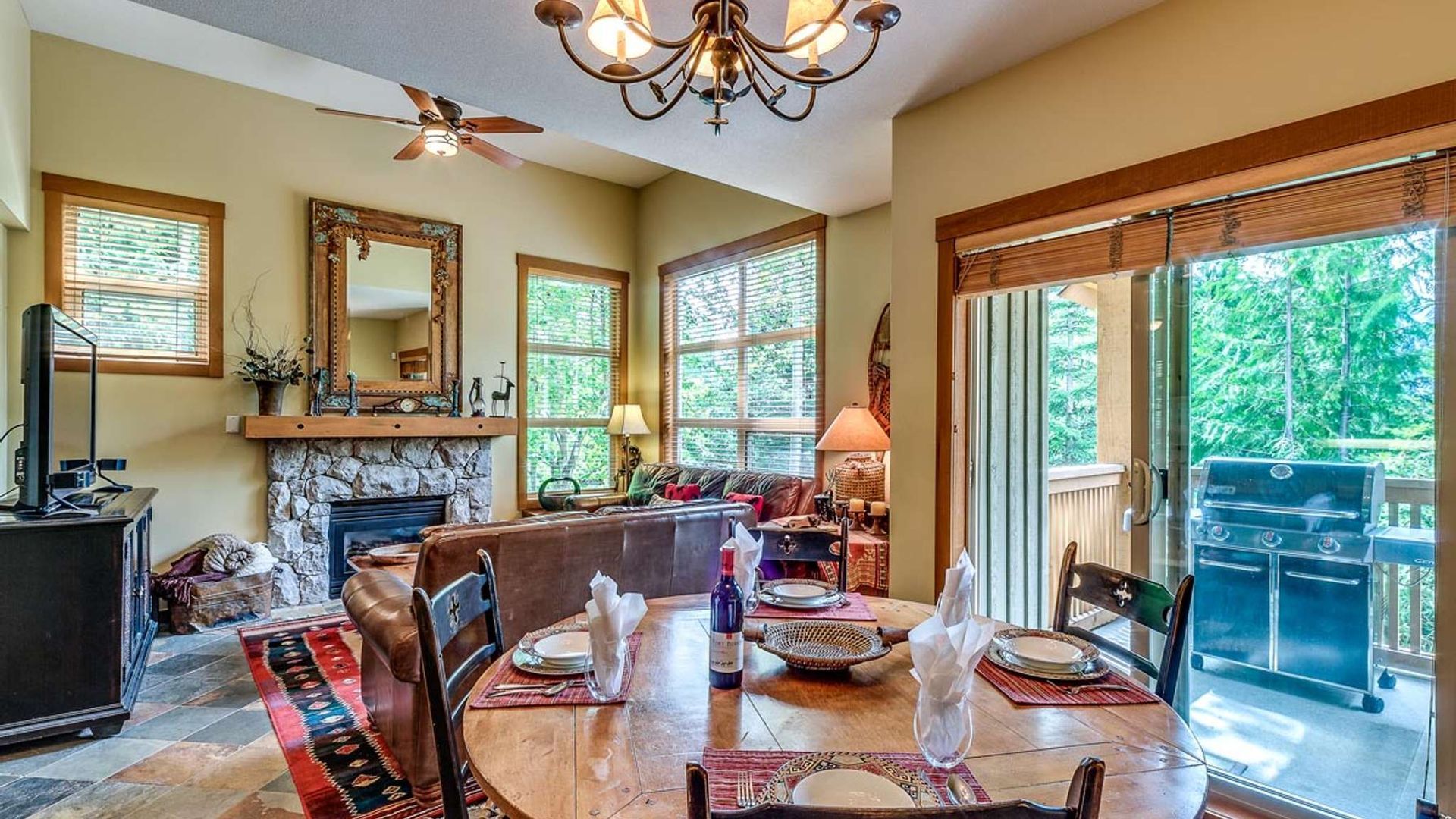 Elegant dining room with stone fireplace, chandelier, wooden table, and sliding glass doors to a patio.