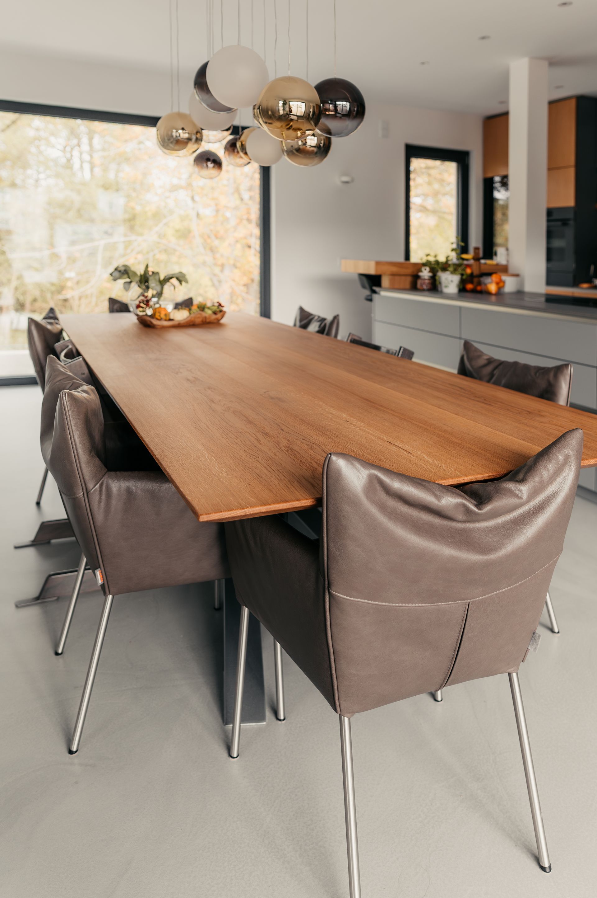 Esszimmer mit großem Holztisch, Lederstühlen und einem Globus-Kronleuchter.