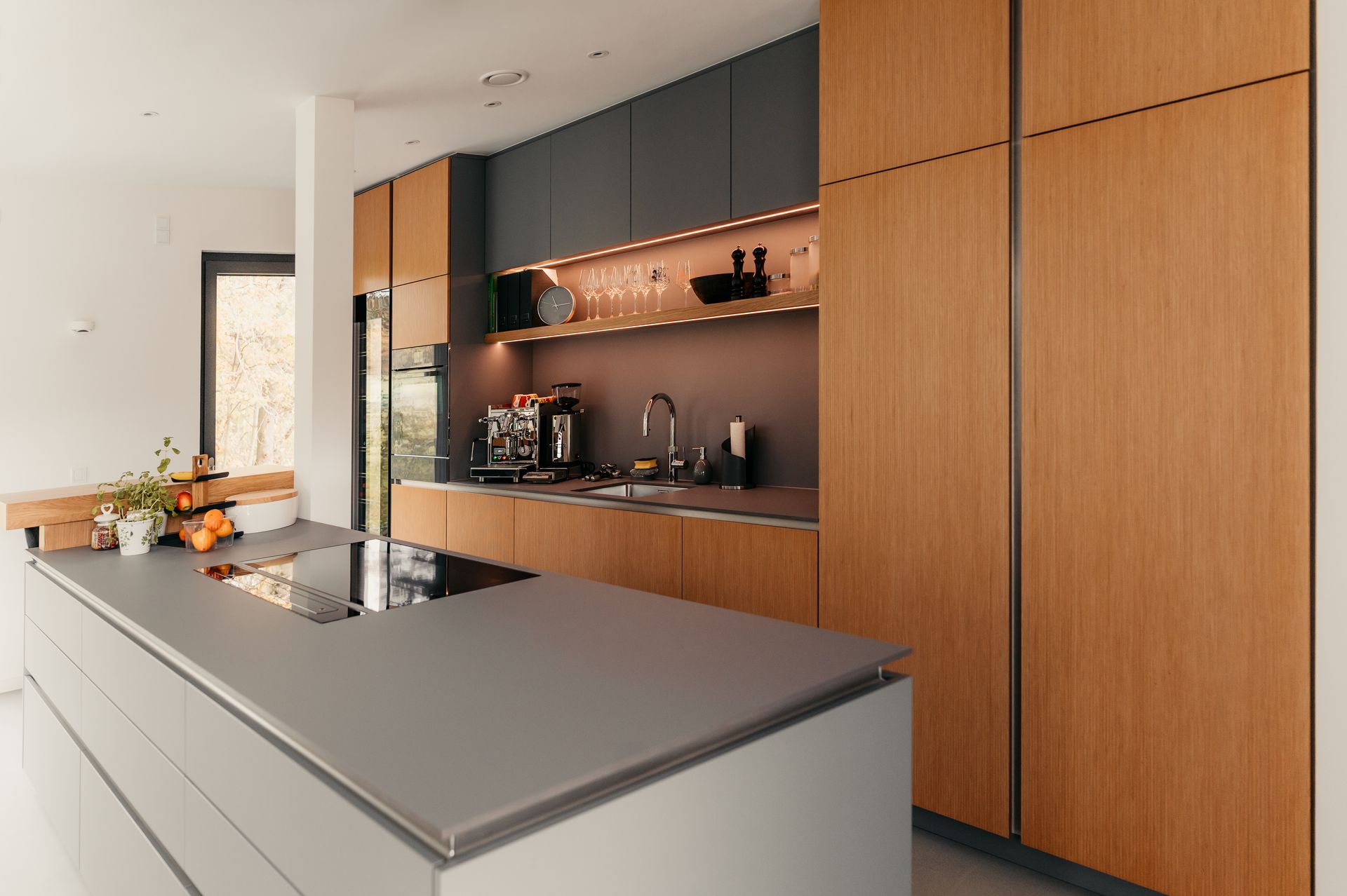 Moderne Küche mit Holz- und Grauschränken, Kochinsel und Geräten aus Edelstahl.