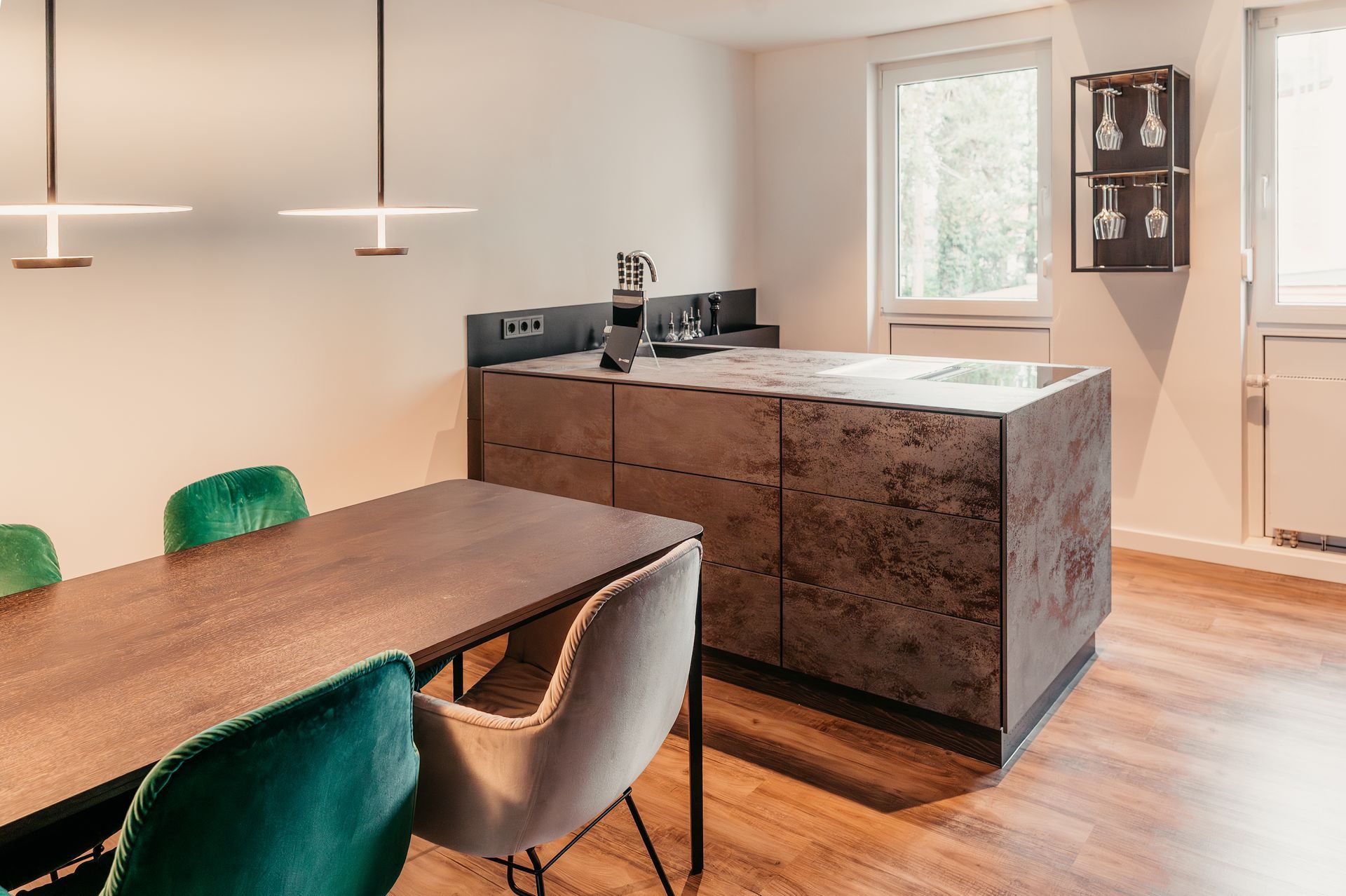 Moderne Küche mit Kochinsel und Esstisch, mit Akzenten aus Holz, Grau und Grün.