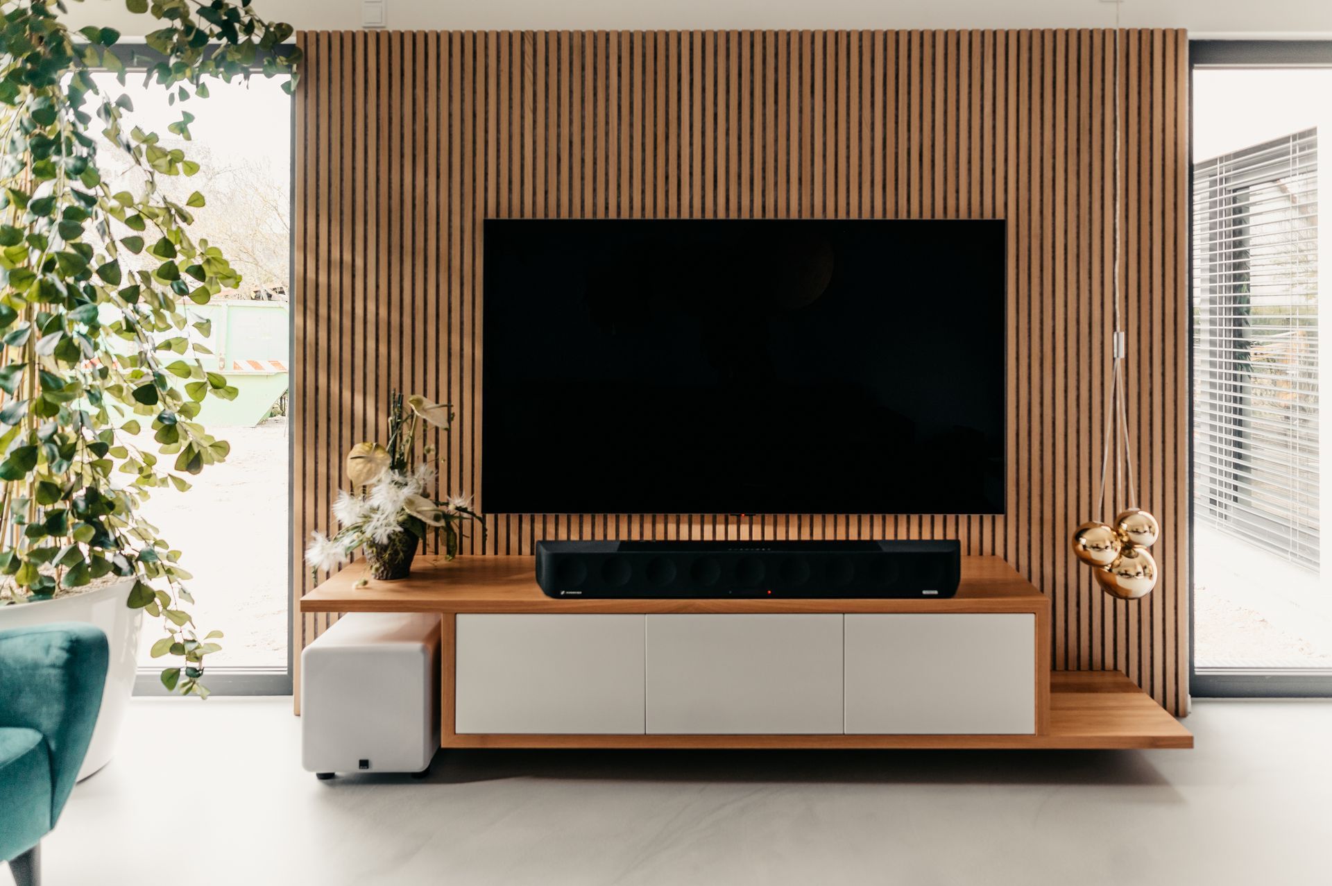 Modernes Wohnzimmer mit großem Fernseher an einer Holzpaneelwand, schwebender Konsole und Soundbar.