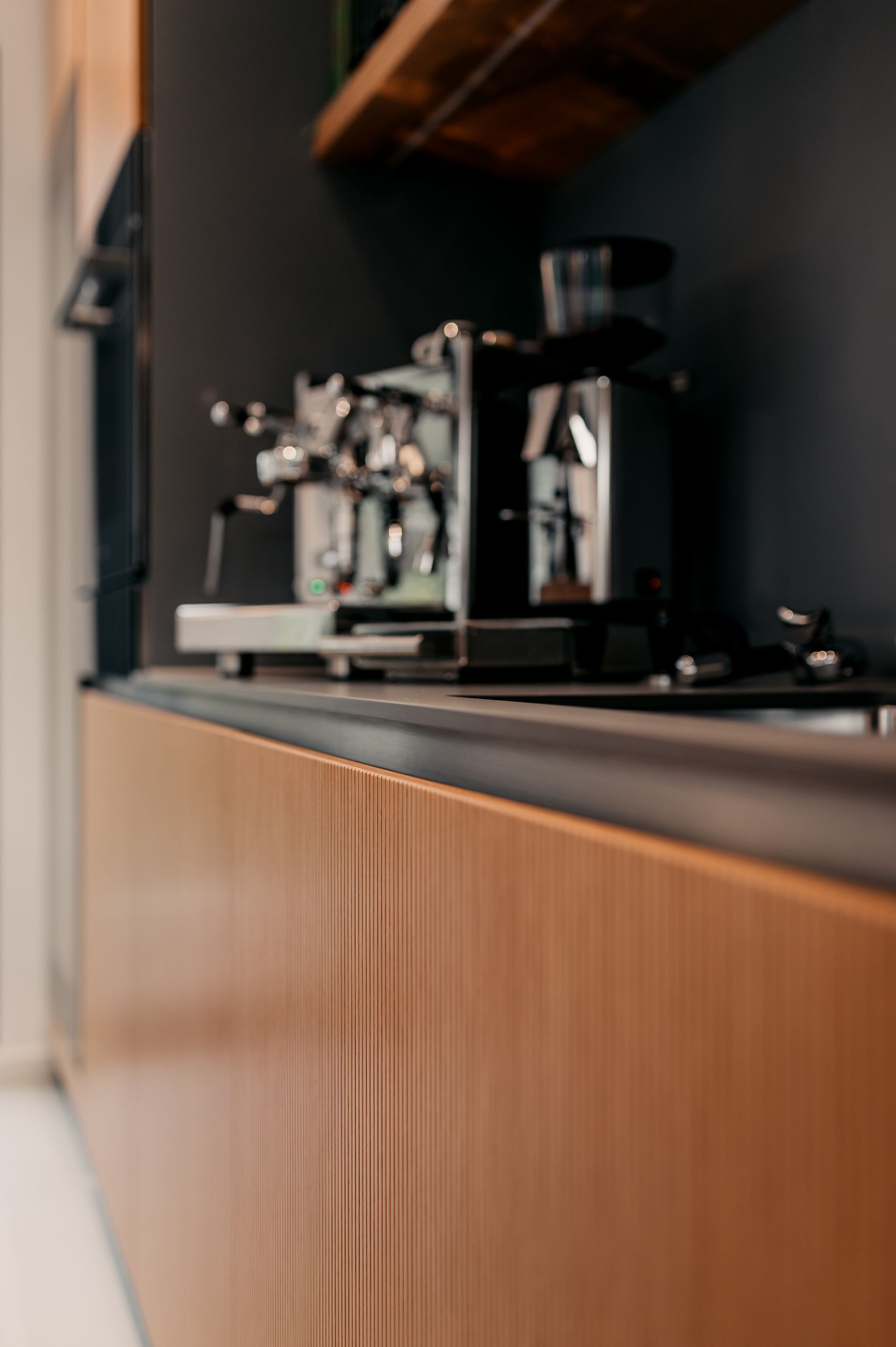 Espressomaschine auf einer Holztheke mit braunen Schränken in einer modernen Küche.