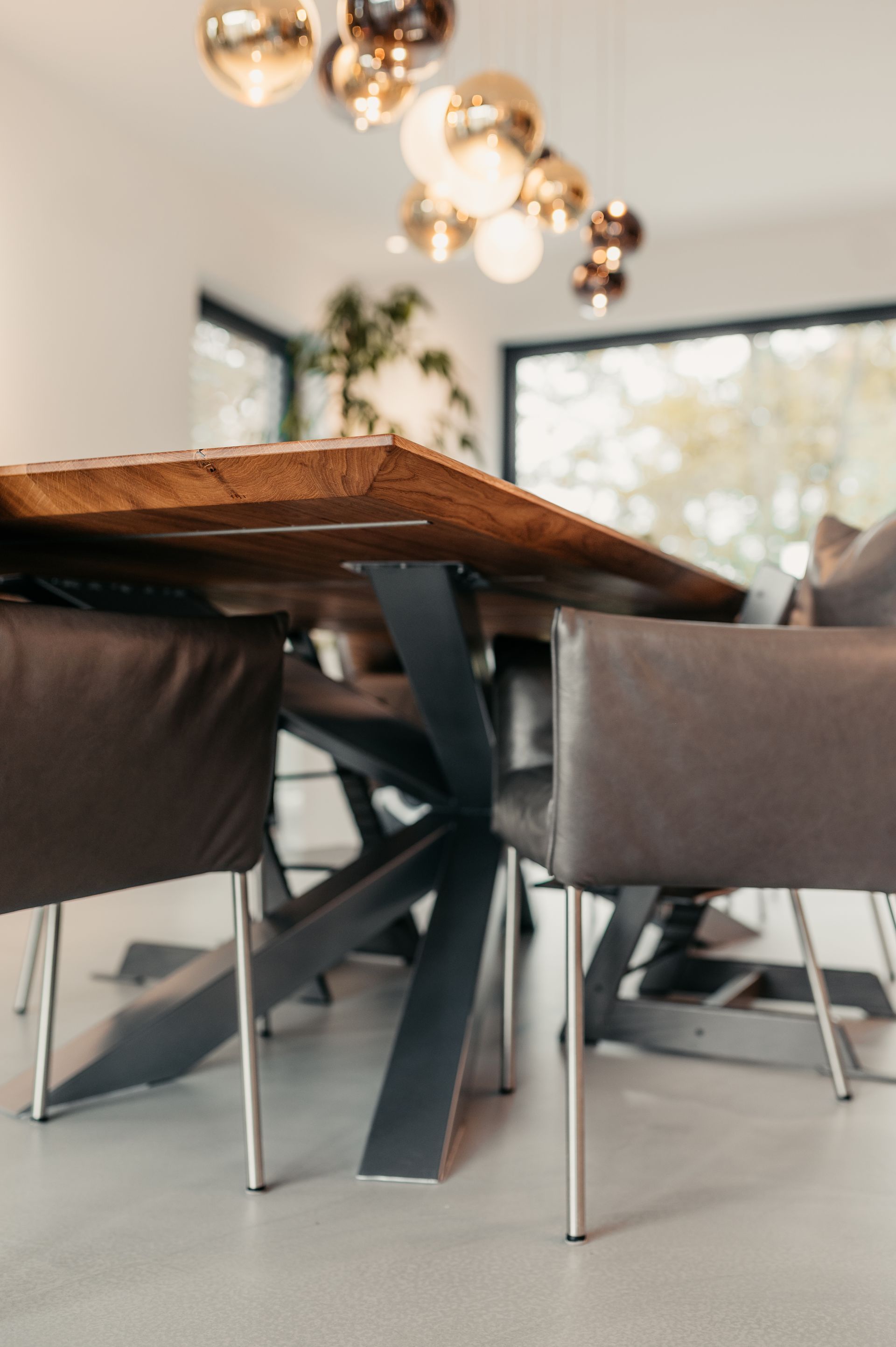 Esstisch mit Holzplatte, schwarzem Metallgestell und grauen Lederstühlen.