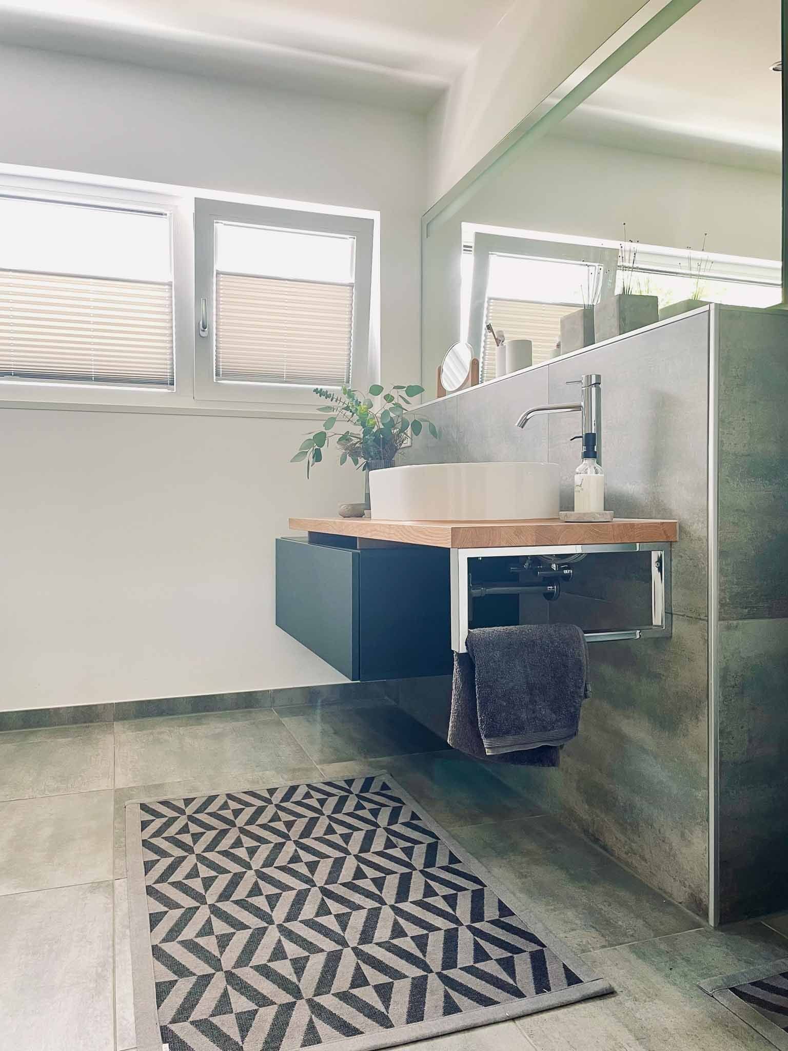 Modernes Badezimmer mit schwebendem Waschtisch, großem Spiegel und geometrischem Teppich.