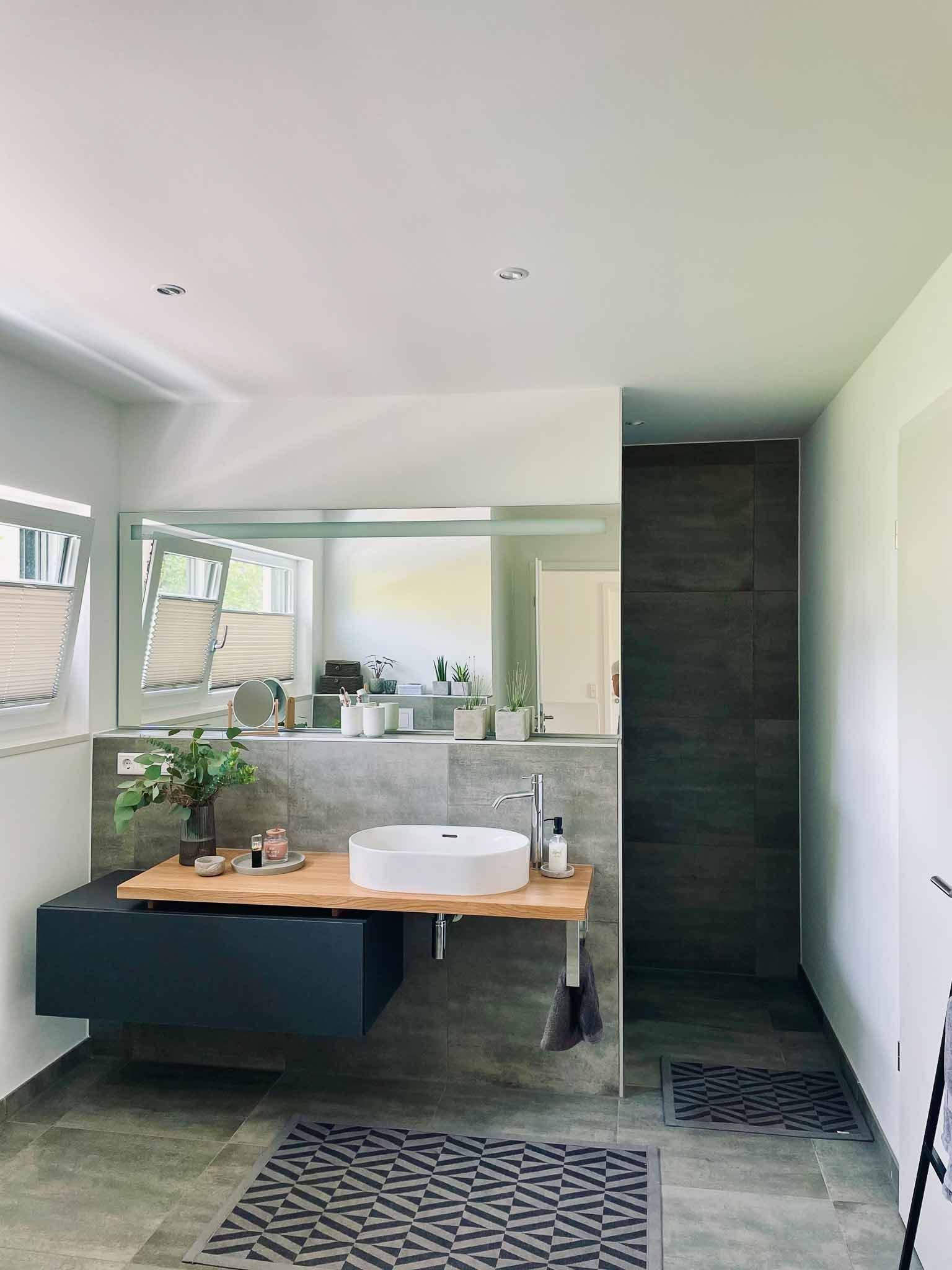 Modernes Badezimmer mit schwebendem Waschtisch, weißem Waschbecken, großem Spiegel und dunkelgrauer Akzentwand.