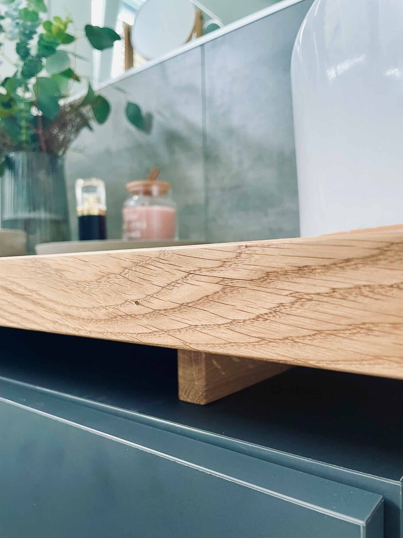 Holzregal, das von einer Holzkonsole über einem grauen Schrank getragen wird; verschiedene Badezimmerartikel auf dem Regal.