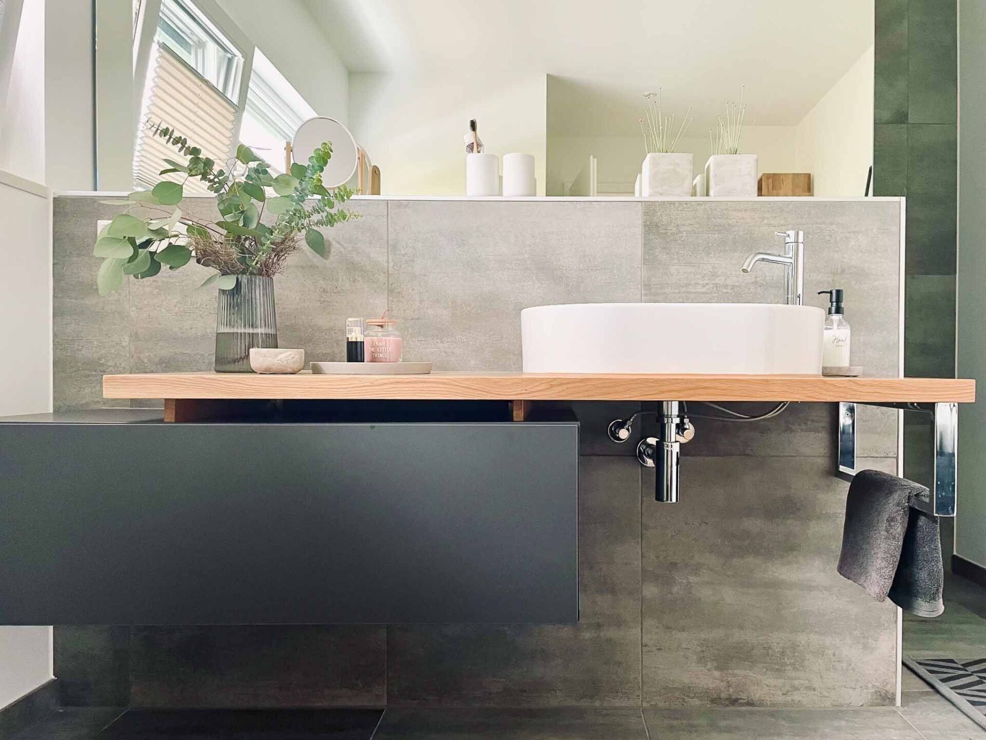 Modernes Badezimmer mit schwebendem Holzregal, Aufsatzwaschbecken und dunkelgrauem Schrank.