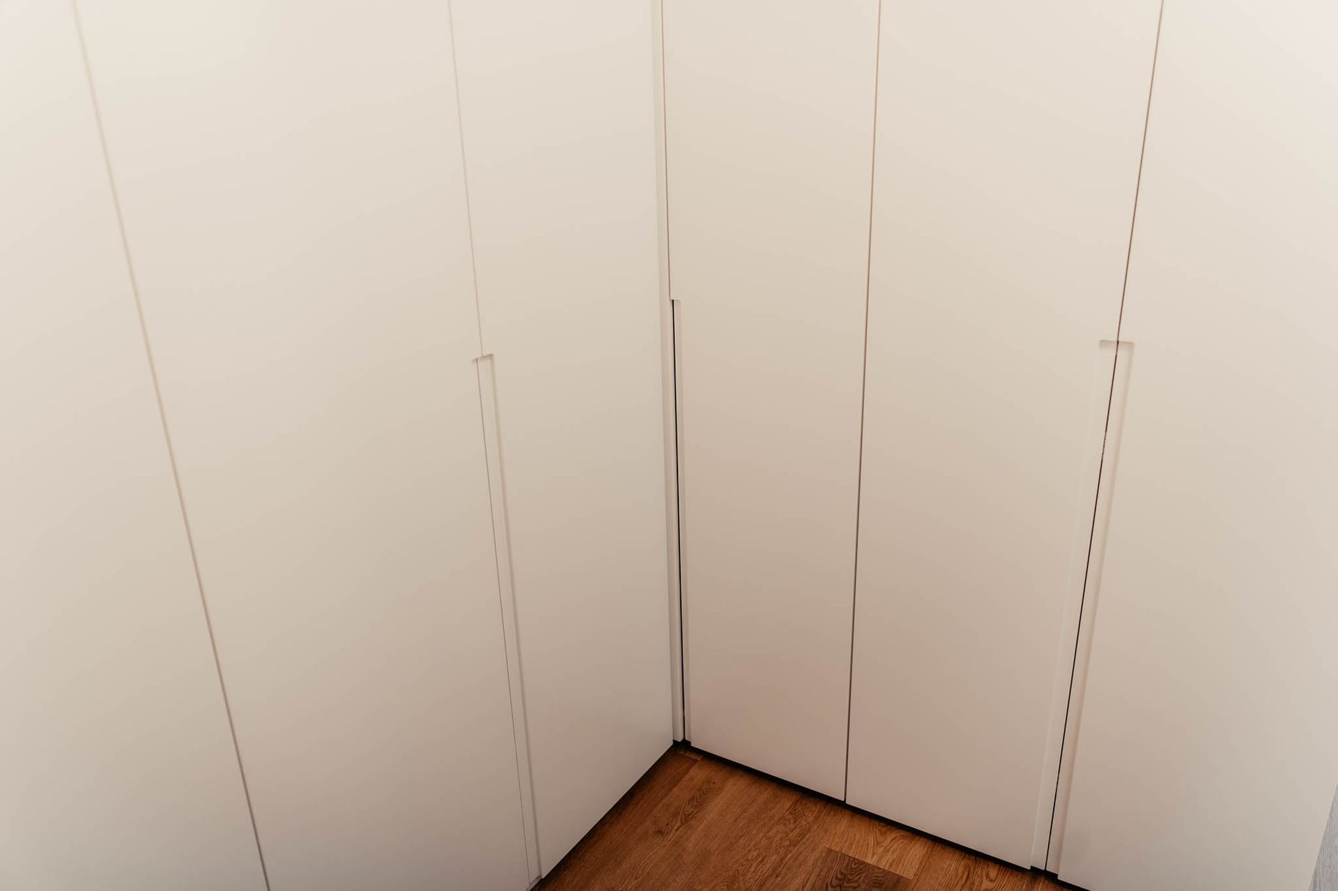 Weiße Schranktüren in einer Ecke mit Holzboden.