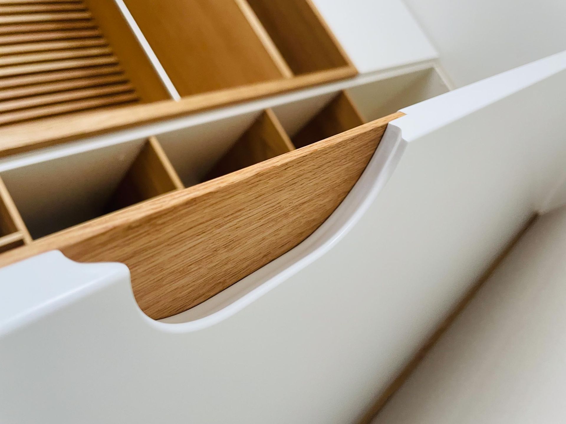 Weiße Schrankschublade mit Organizerfächern aus Bambus.