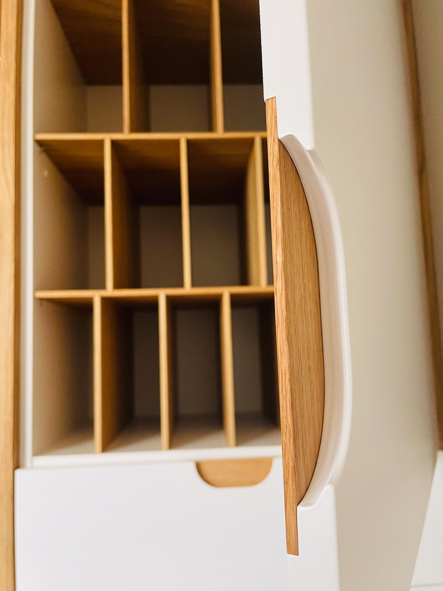 Weißer Schrank aus Holz mit offener Tür und mehreren Fächern.