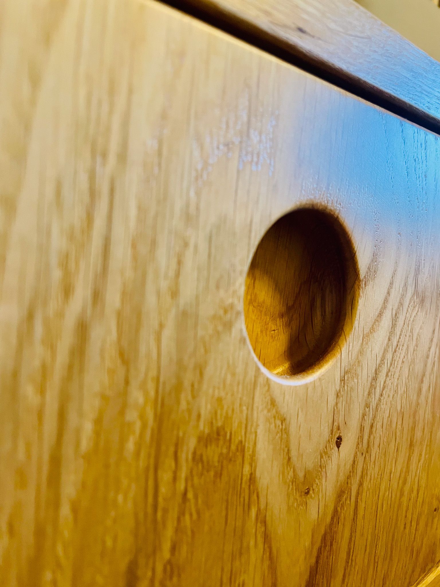 Holzschrankdetail mit kreisförmigem Griffausschnitt.