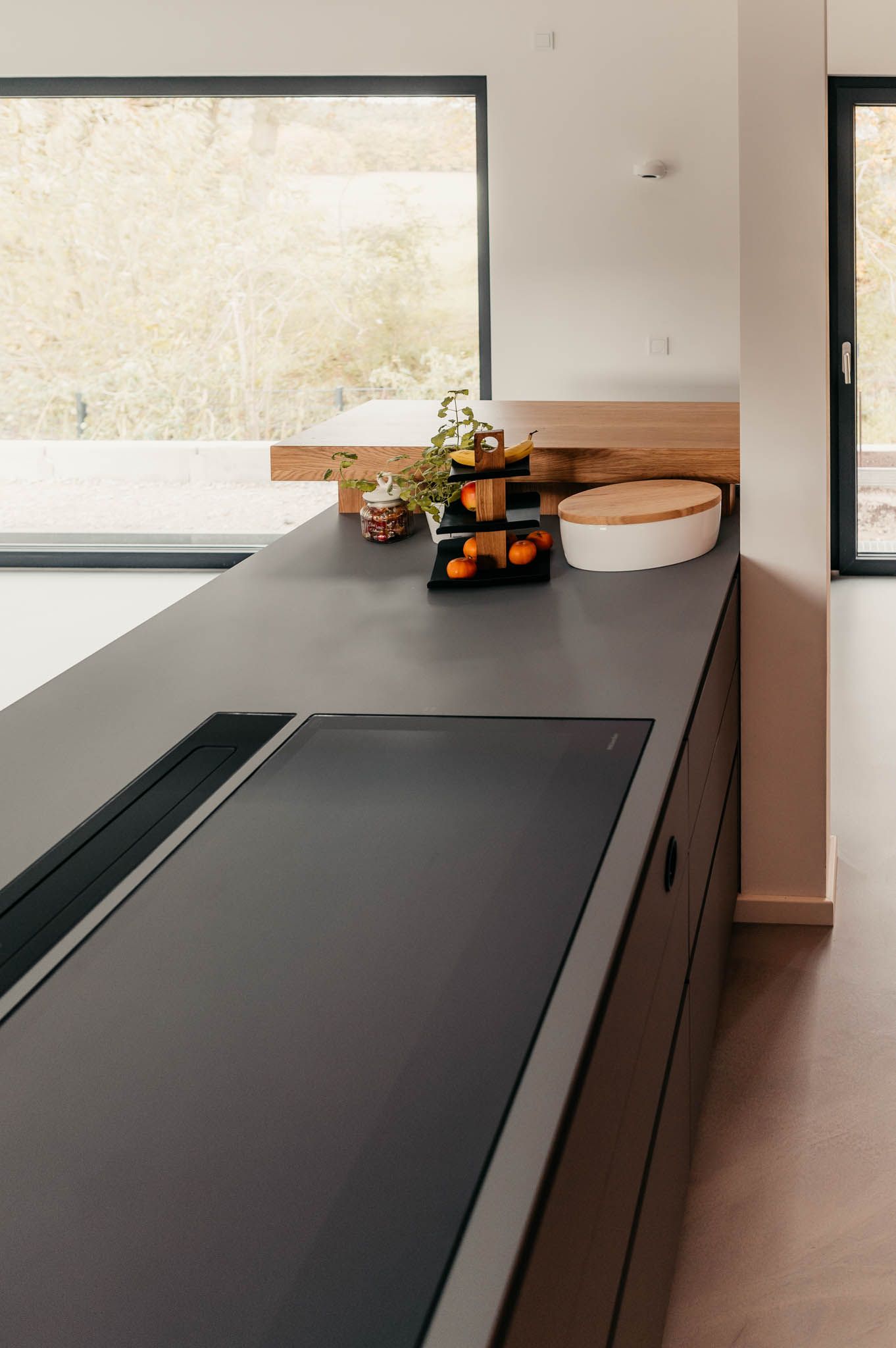 Moderne Küchentheke mit Herd, Obst und Grünpflanzen.