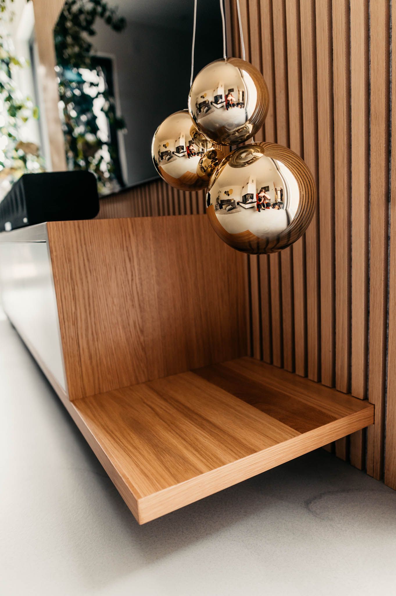 Eckregal aus Holz mit goldenem Weihnachtsschmuck in einem modernen Interieur.