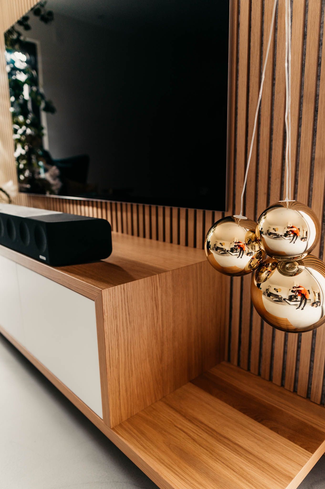 Modernes Entertainment-Center mit Fernseher, Lautsprecher, Goldornamenten und Holzvertäfelung.