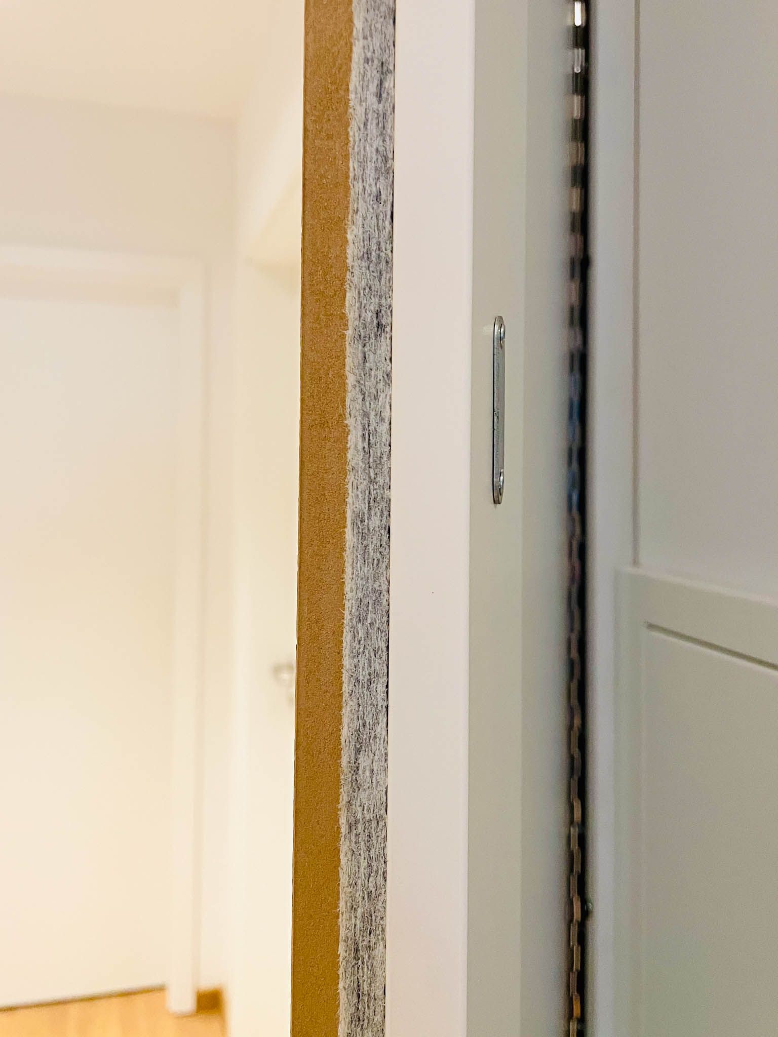 Schichten einer Wand mit freiliegenden braunen, grauen und weißen Abschnitten, neben einem geschlossenen Türrahmen.