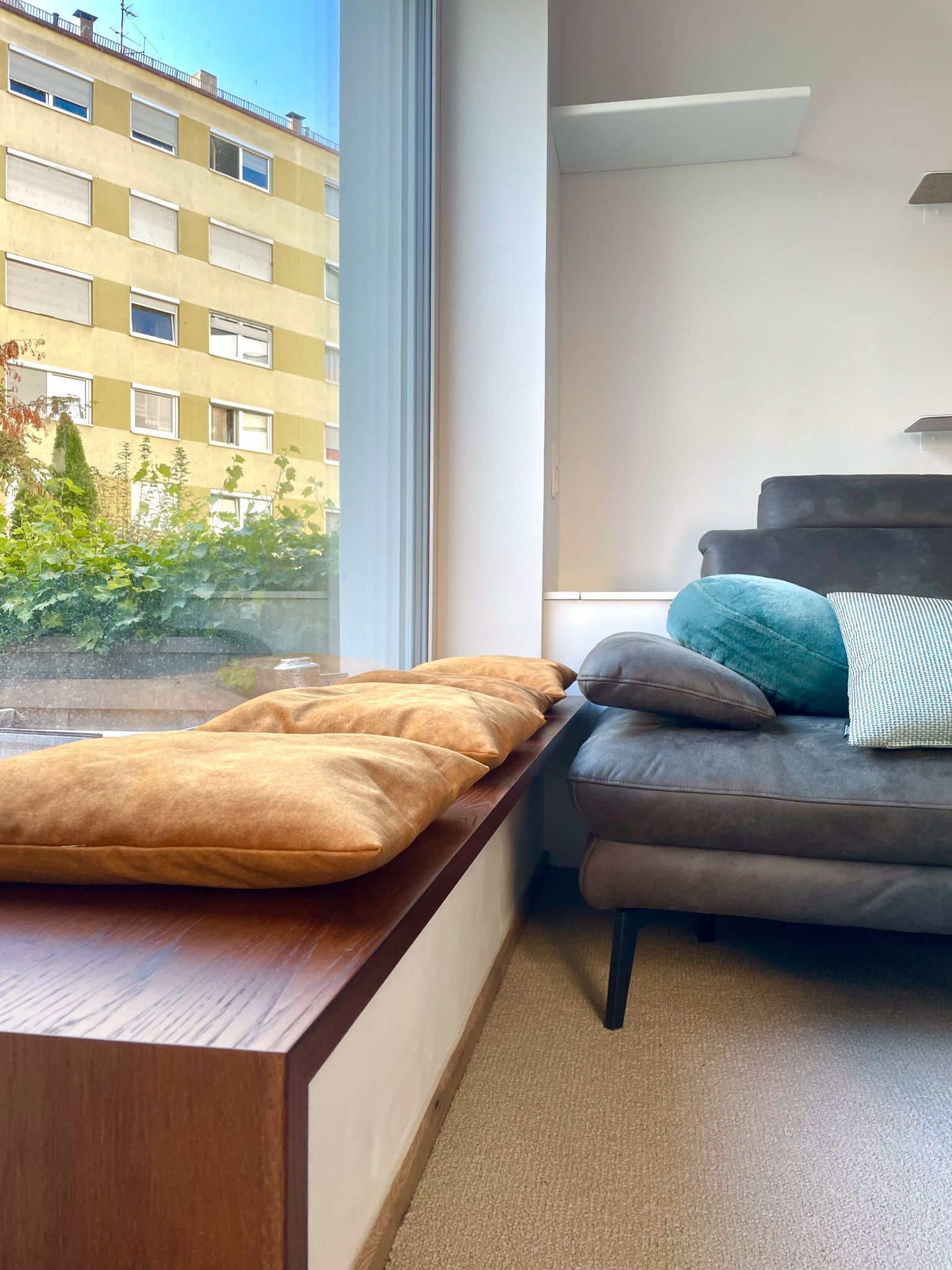 Fensterplatz mit goldenen Kissen, Sofa mit blauen Kissen. Wohnungsfenster, Außenansicht.