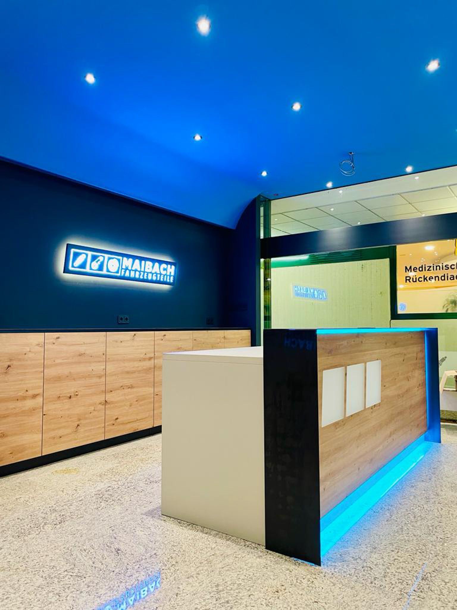 Modernes Bürointerieur mit Empfangstresen, Blau- und Holztönen und einem leuchtenden Schild.