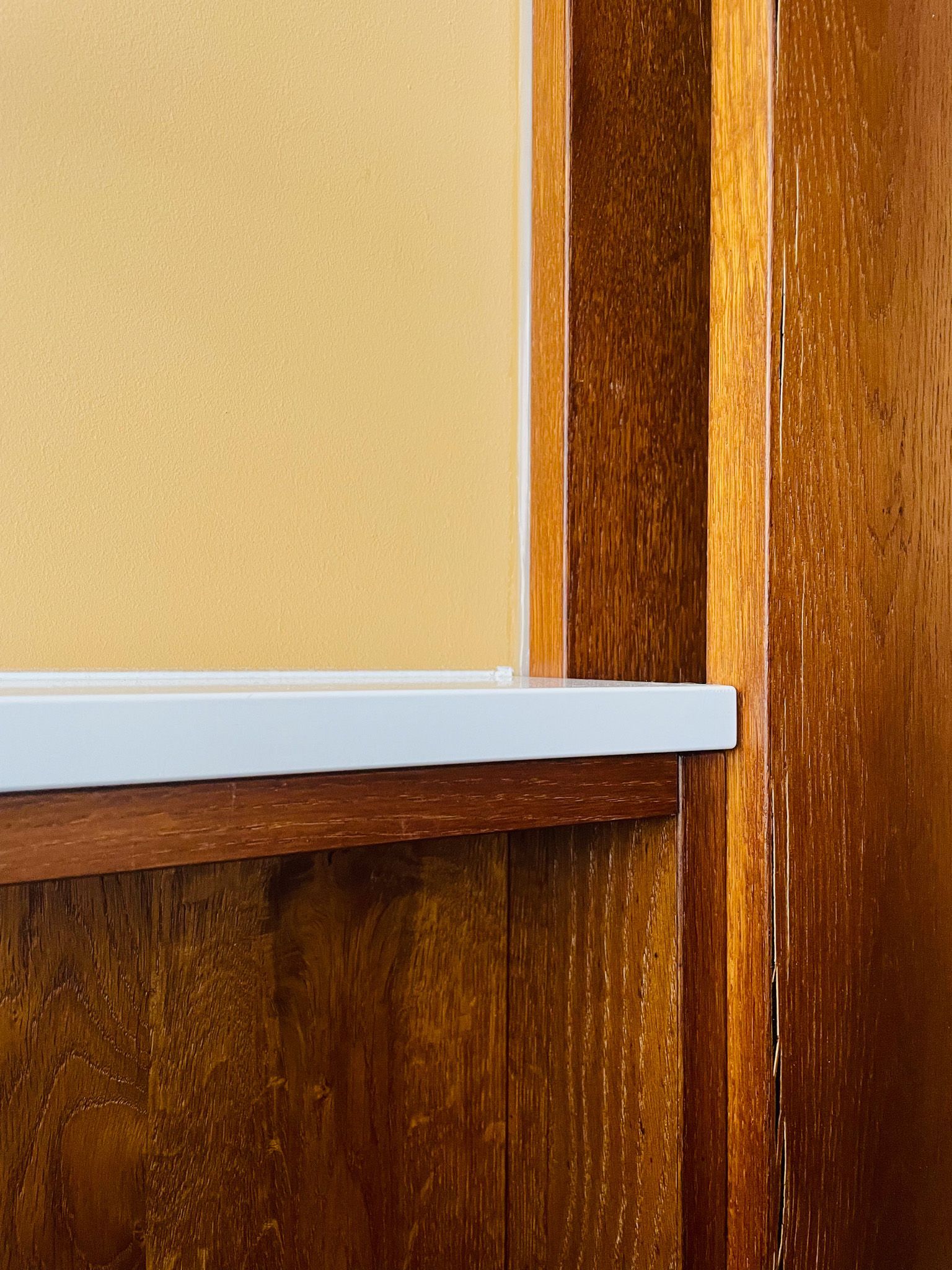 Eckschrank aus Holz mit weißem Regal und hellbrauner Wand.