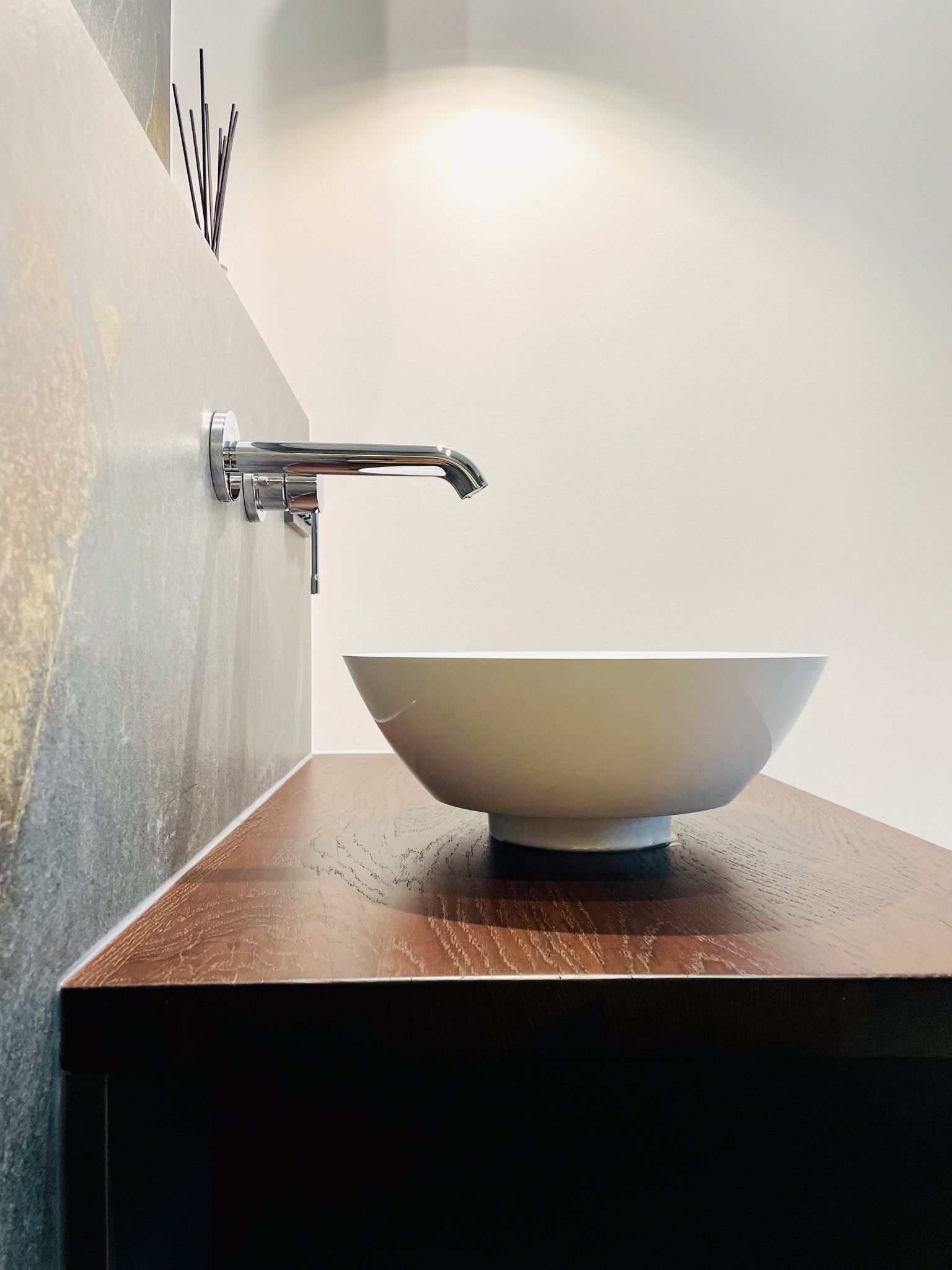 Ein weißes Waschbecken auf einem dunklen Holzschrank mit einem silbernen Wasserhahn.