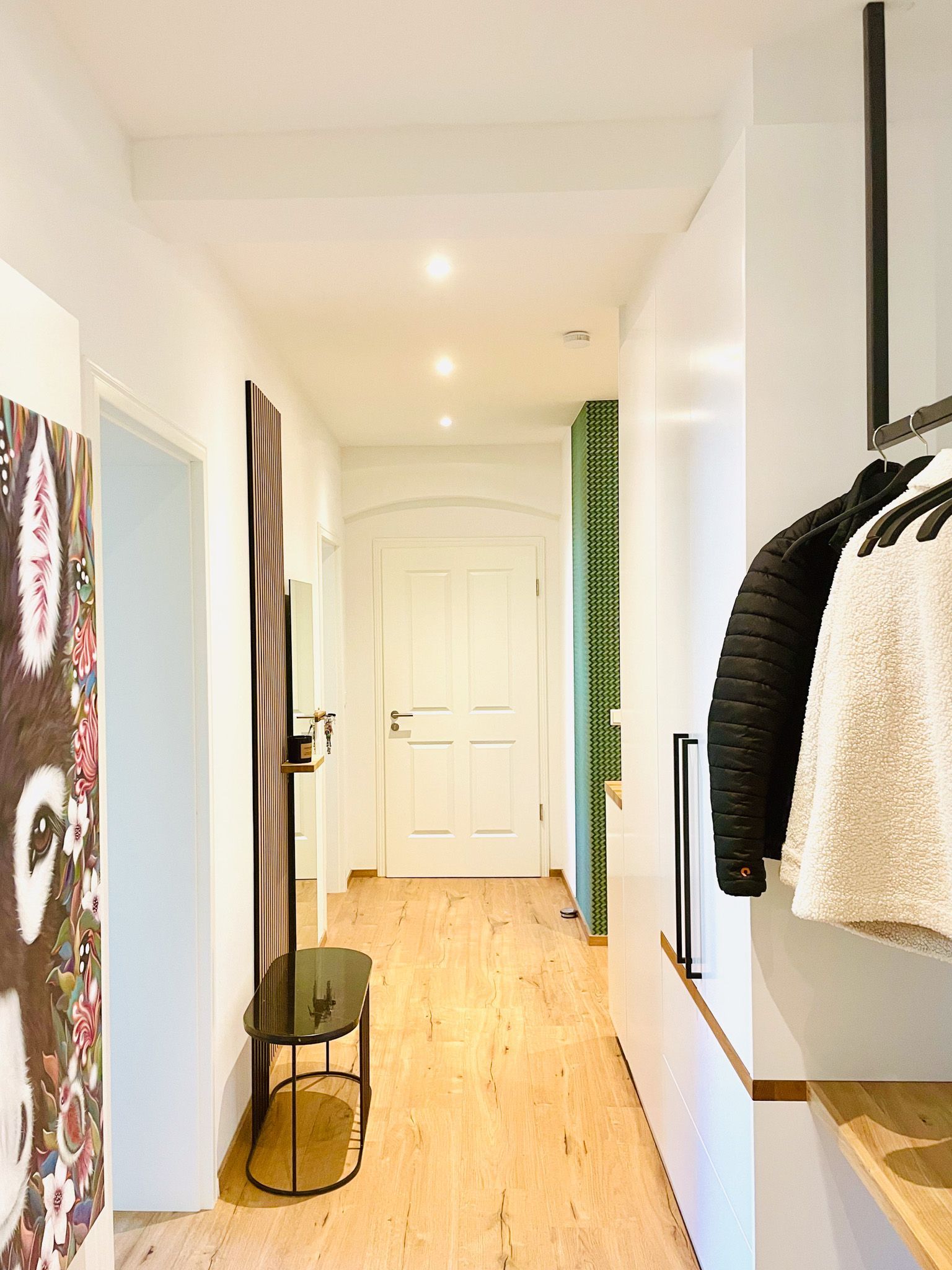 Langer Flur mit weißen Wänden, Holzboden und Kleiderschrank.