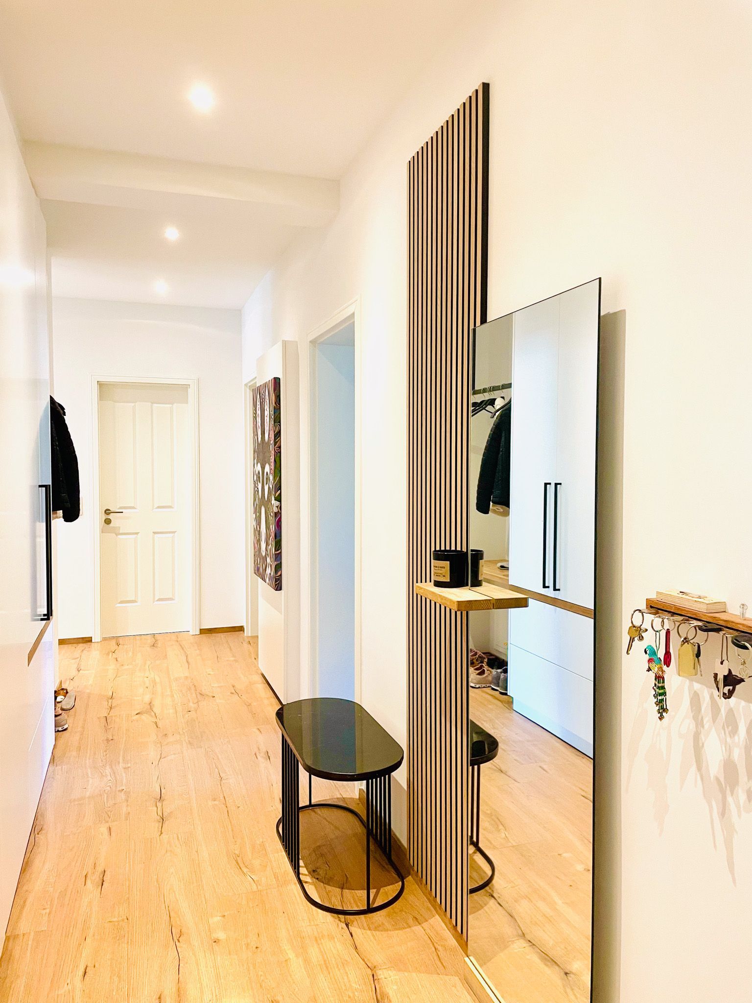 Langer Flur mit Holzboden, einem großen Spiegel und einer Bank.