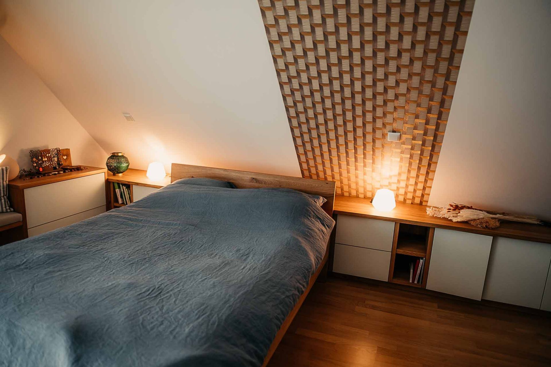 Gemütliches Schlafzimmer mit einem Bett, einem Kopfteil und Schränken aus Holz sowie warmer Beleuchtung.