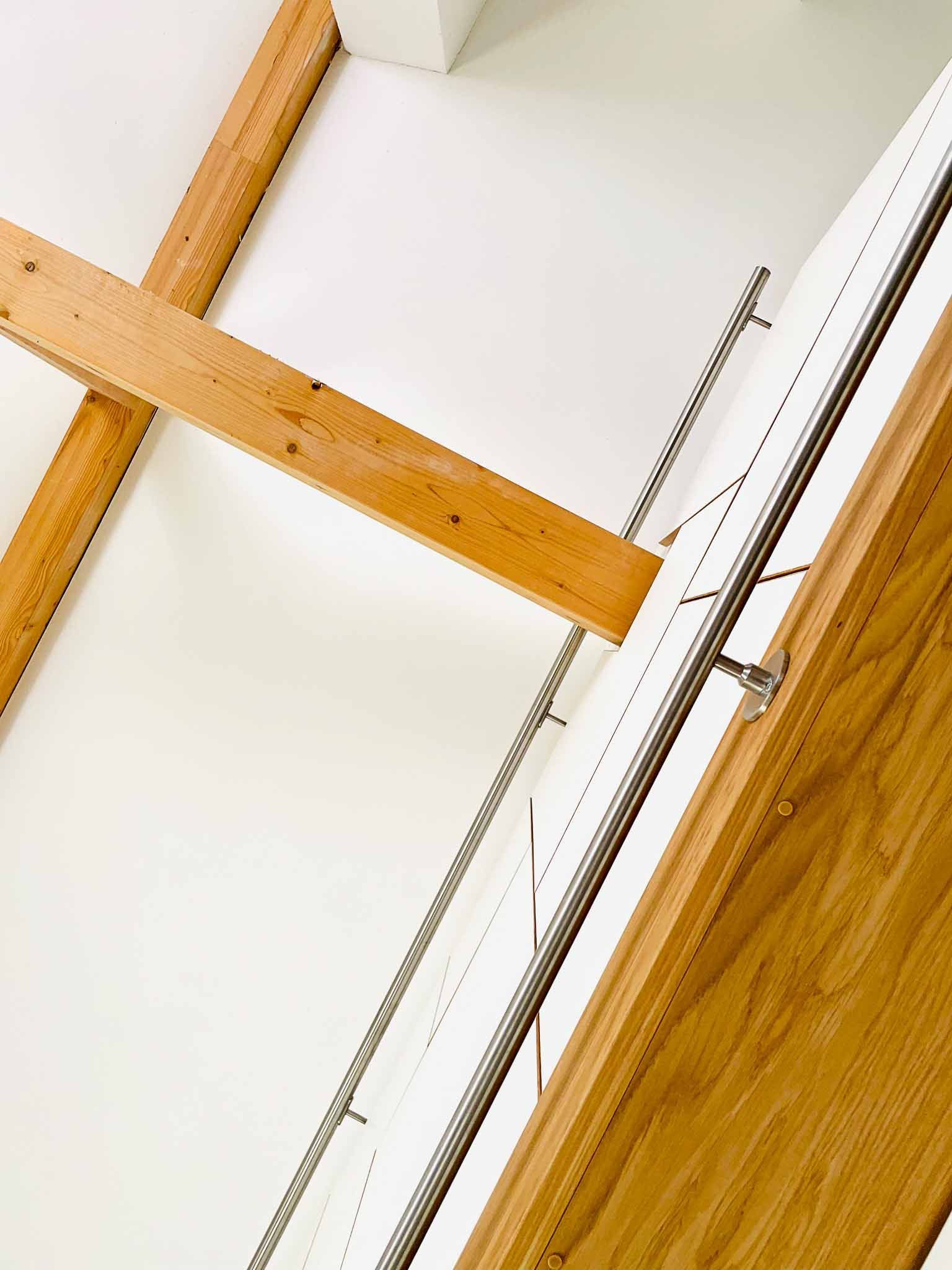 Holzbalken kreuzen sich mit einer weißen Wand und einer Holztür.