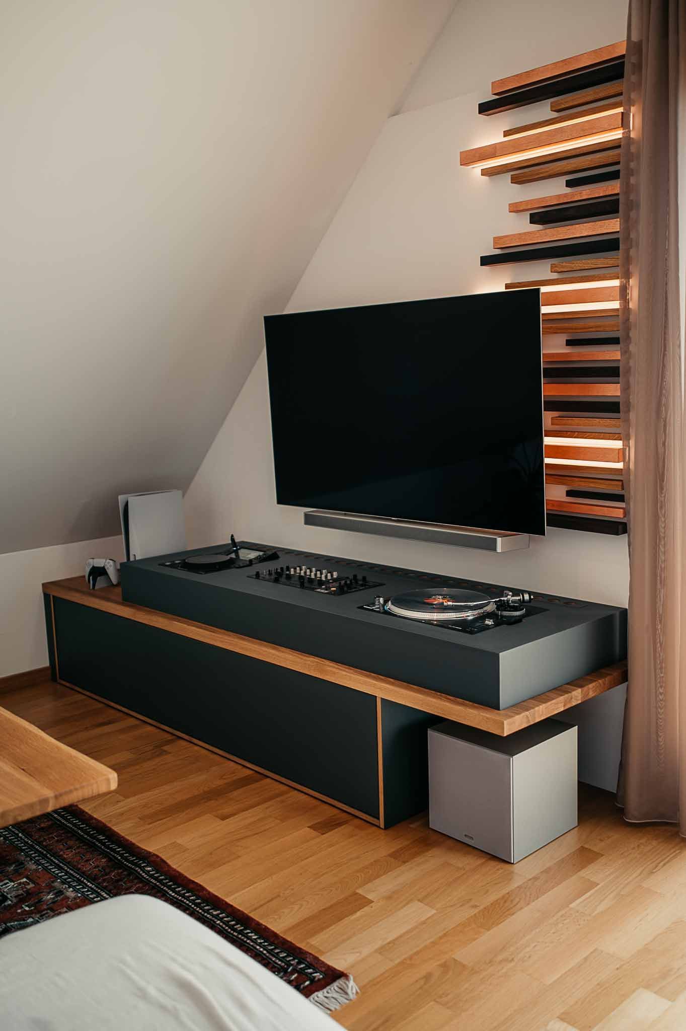 Ein modernes Wohnzimmer mit Fernseher, Soundsystem und einer Akzentwand aus Holz.