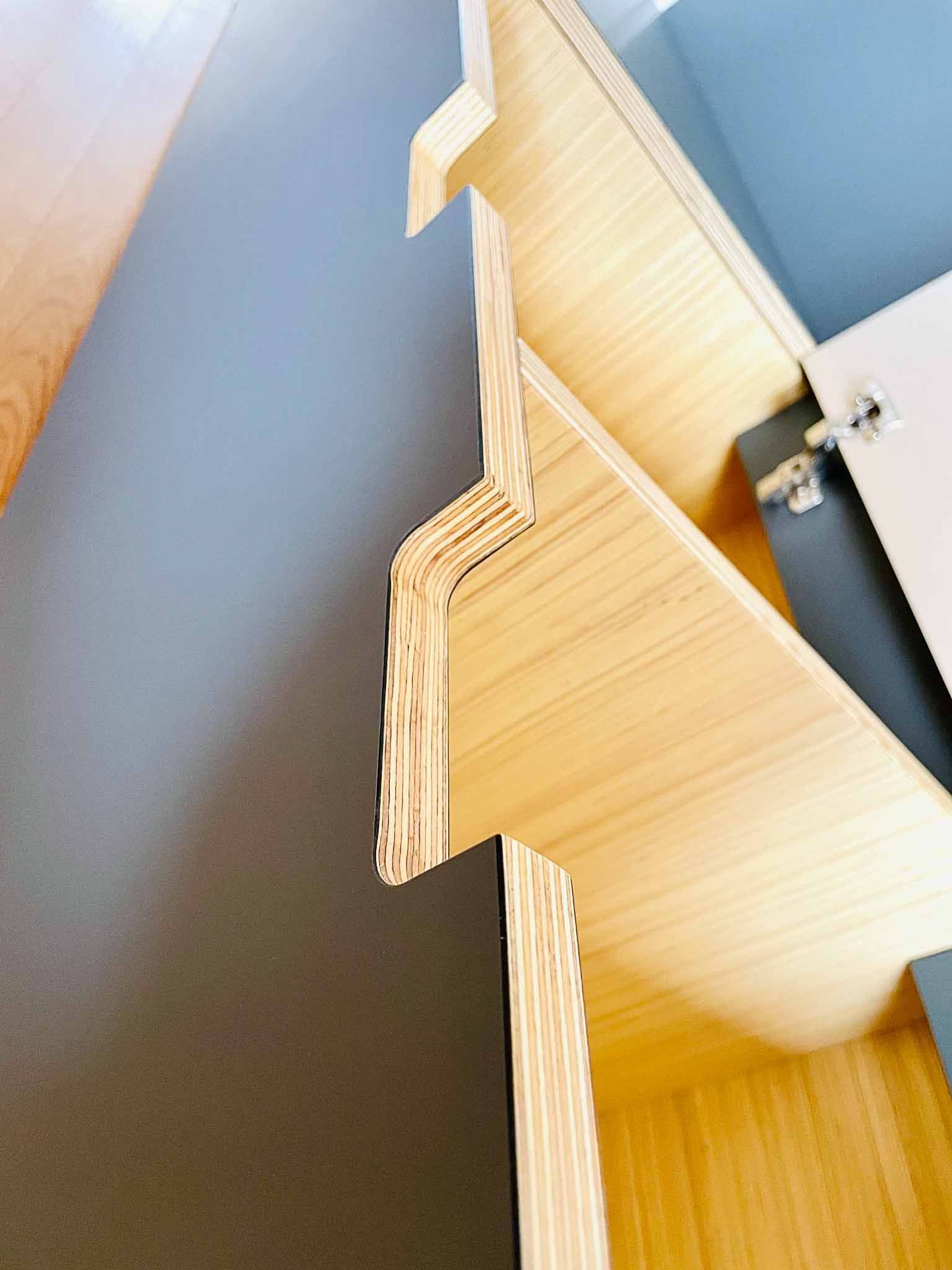 Helles Holzregal mit grauer Wand und weißem Schrank.