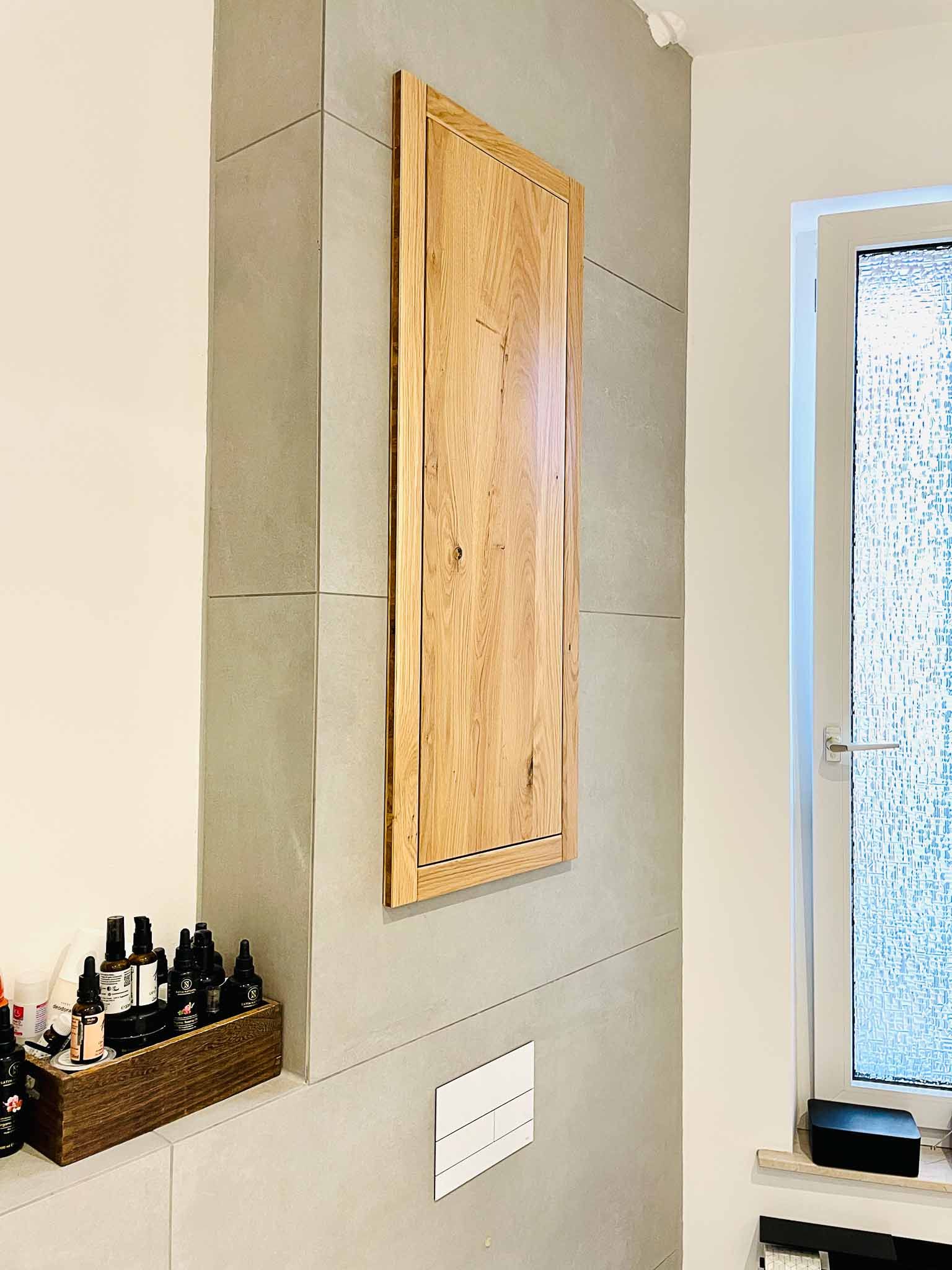 Holzschrank an einer grauen Wand mit einem Fenster und einem Korb mit Gegenständen in der Nähe.