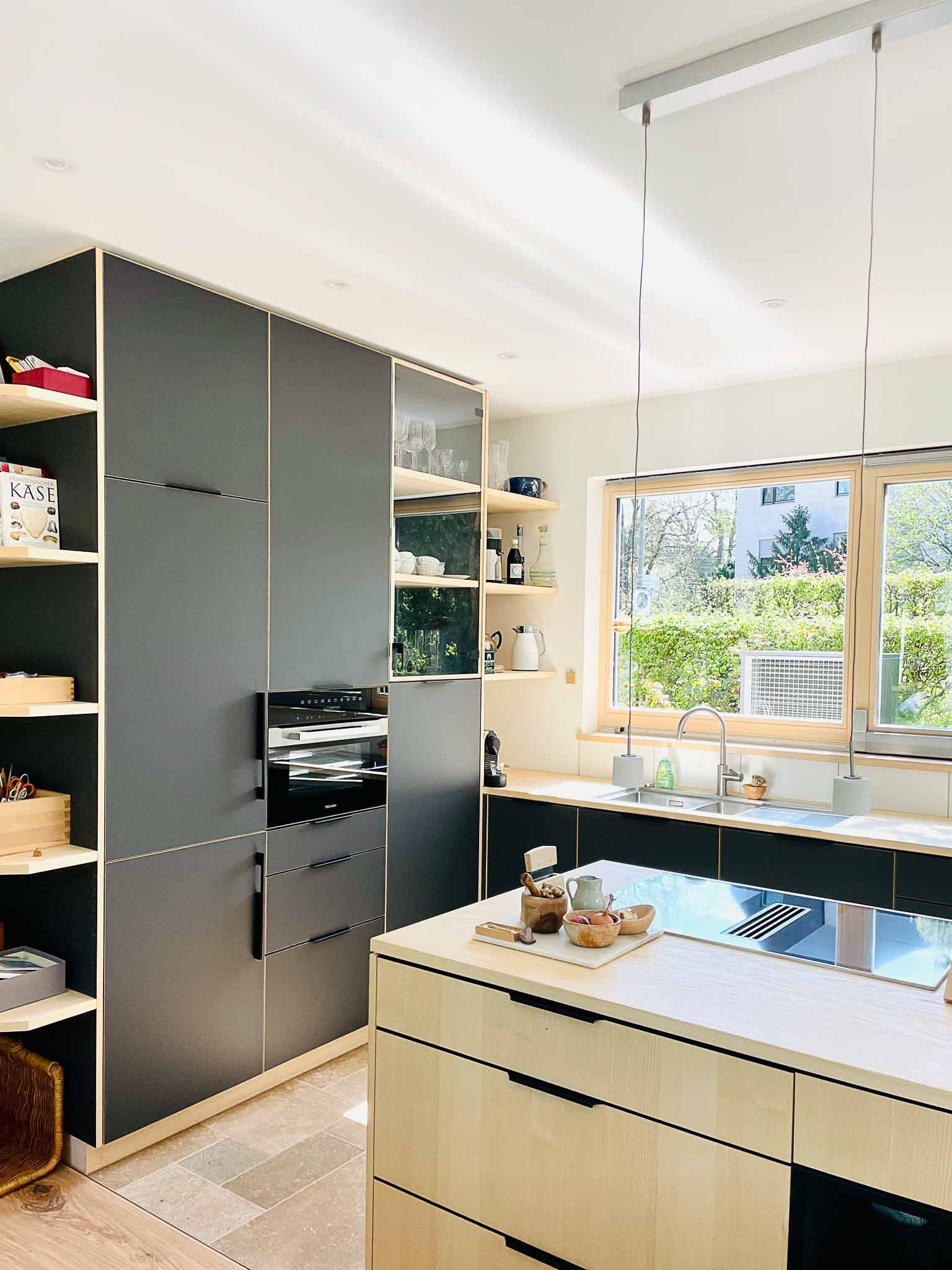 Moderne Küche mit dunkelgrauen Schränken und hellen Holzakzenten.