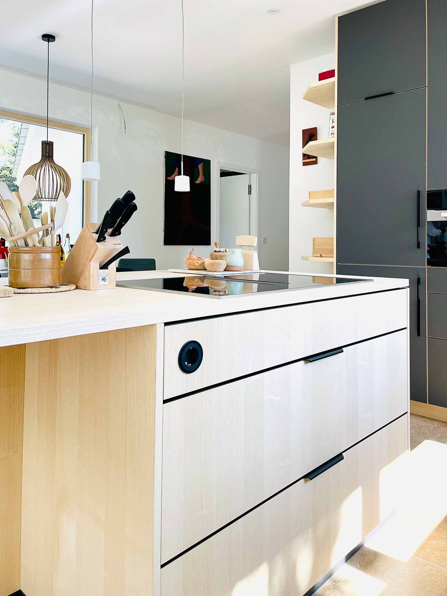 Moderne Kücheninsel mit hellem Holz und schwarzen Akzenten.