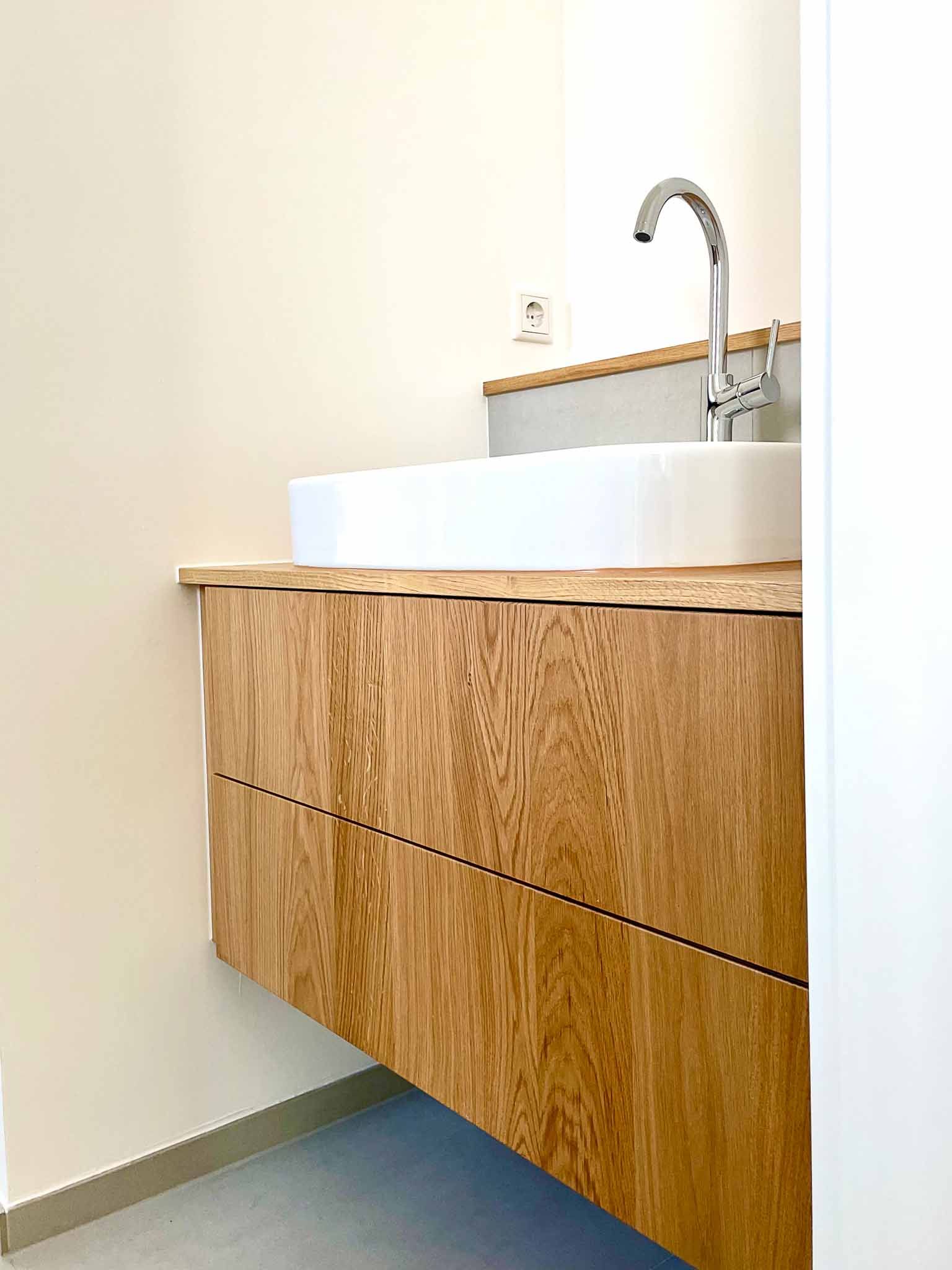 Badezimmerwaschtisch aus Holz mit weißem rechteckigem Waschbecken und Chromhahn.