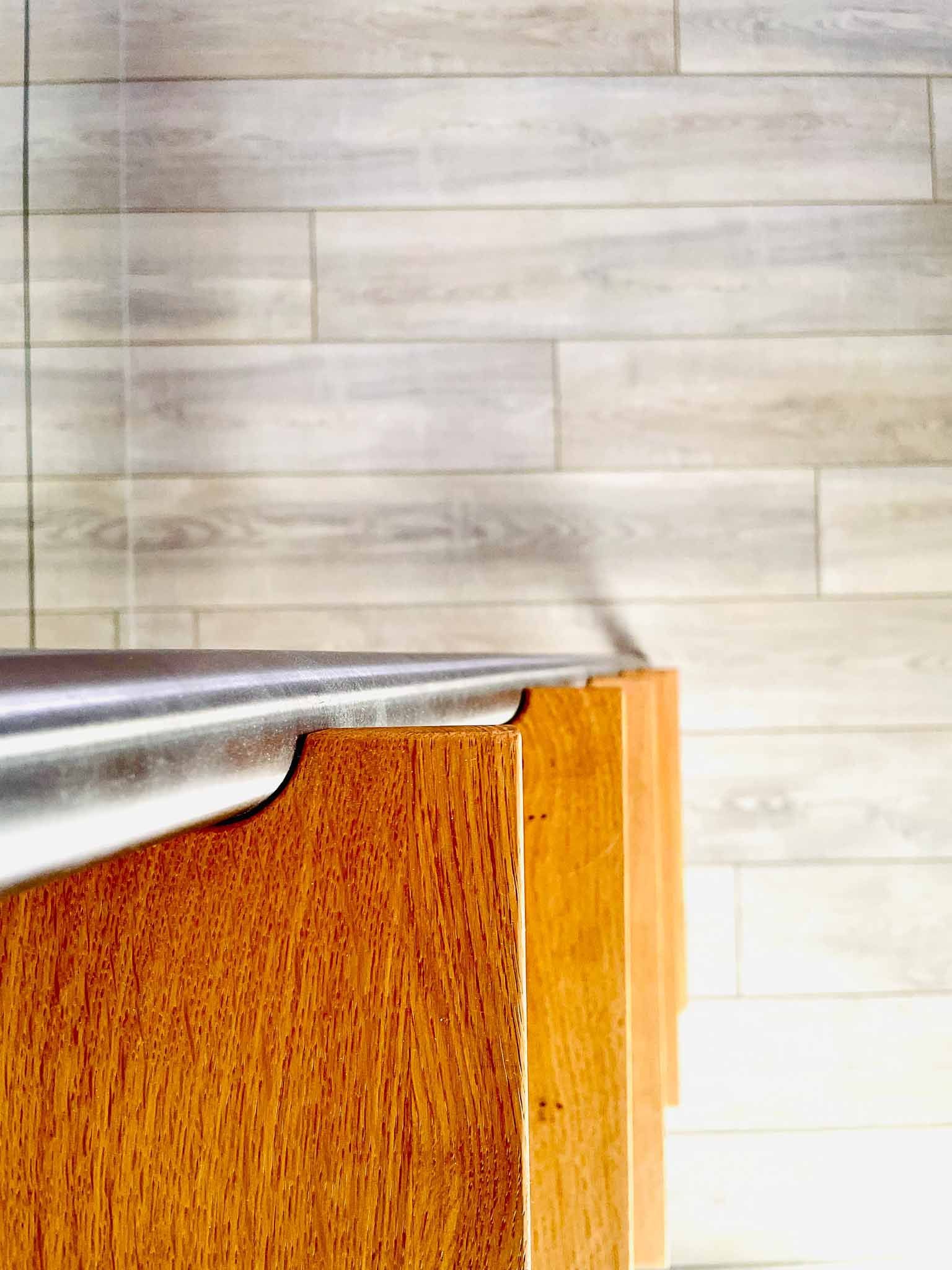 Holzschreibtisch mit silberner Kante vor einer hell holzgetäfelten Wand.