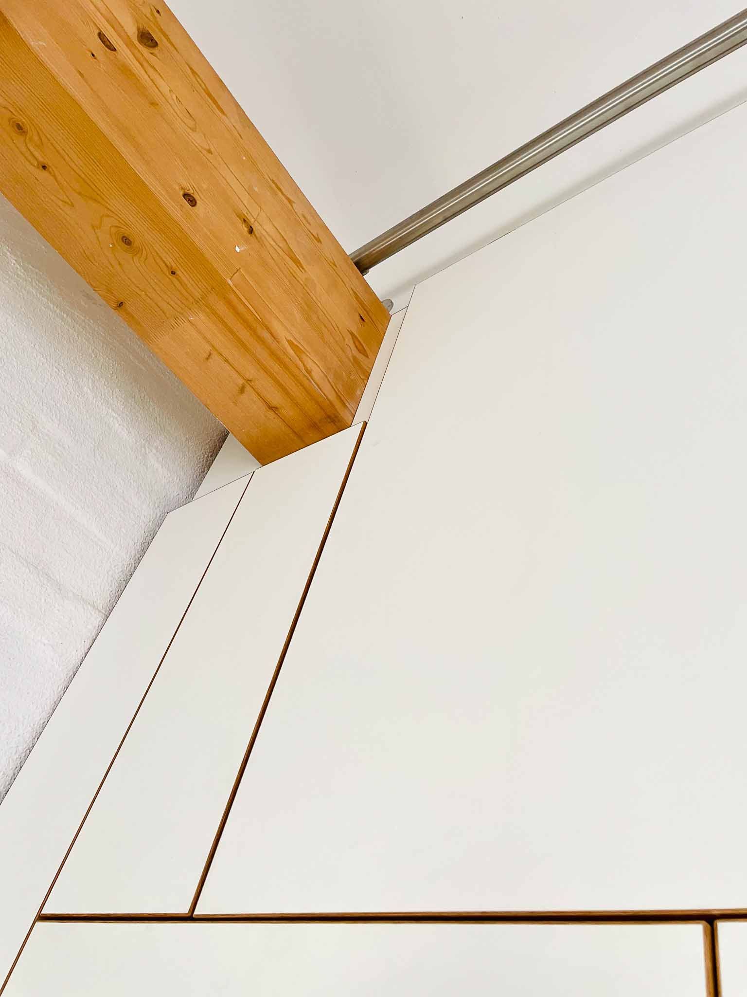 Holzbalken, die weiße Wandpaneele kreuzen, möglicherweise eine Innendecke.