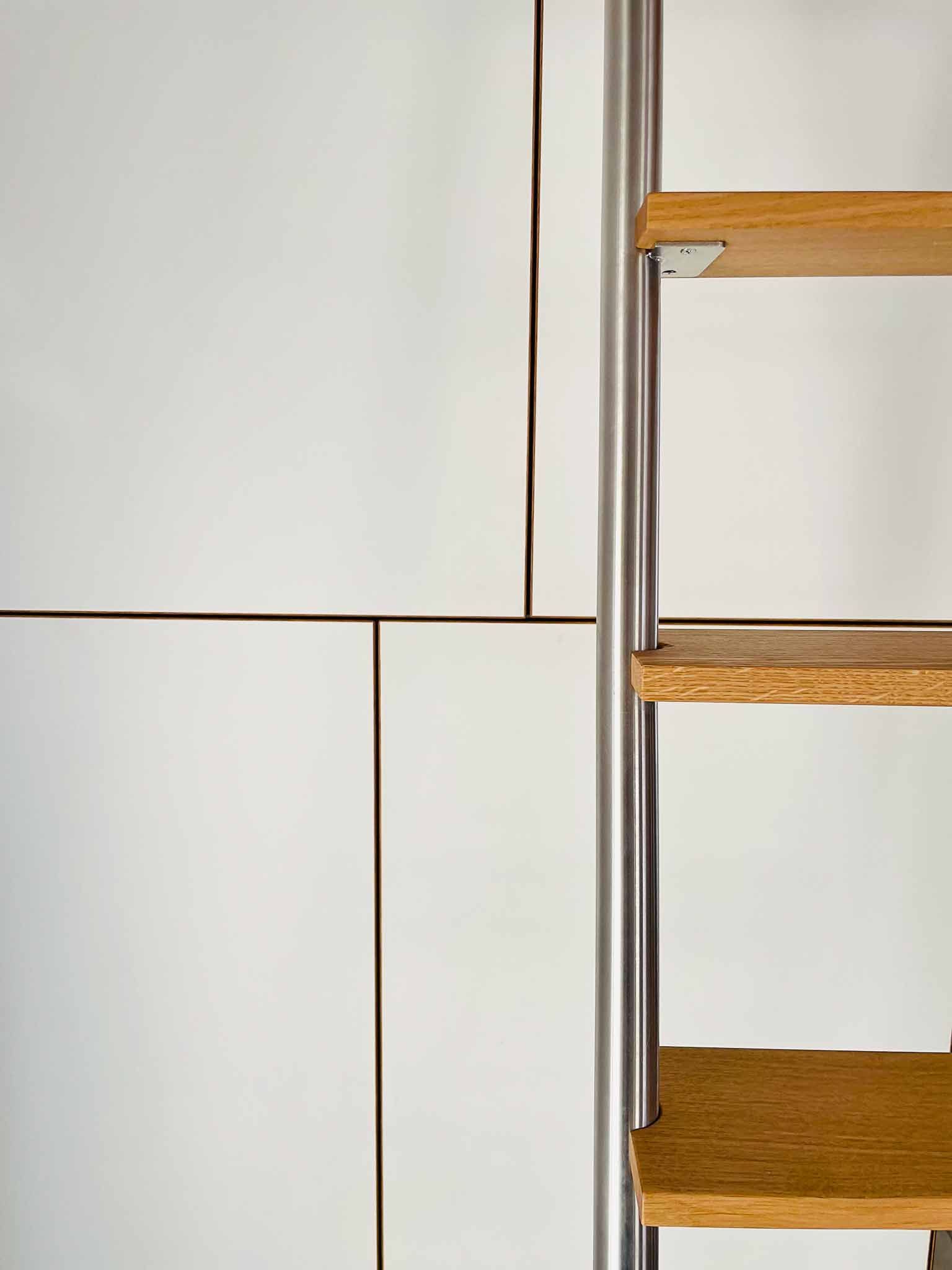 Eine weiße Wand mit Holzpaneelen und einer Metallleiter mit Holzstufen.
